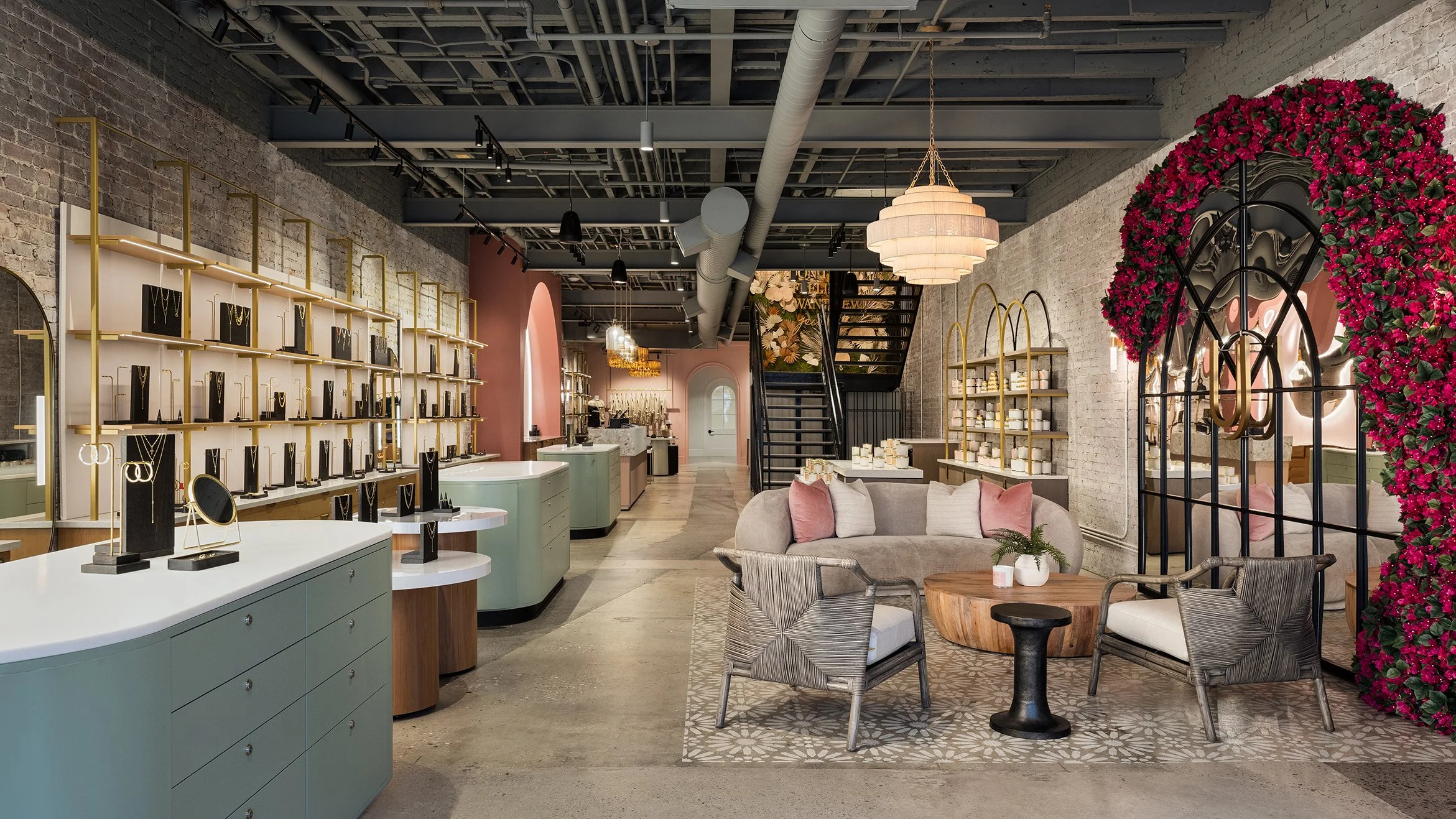 Interior of a trendy jewelry store with display shelves, a seating area with cushions, and a large floral wall decoration.
