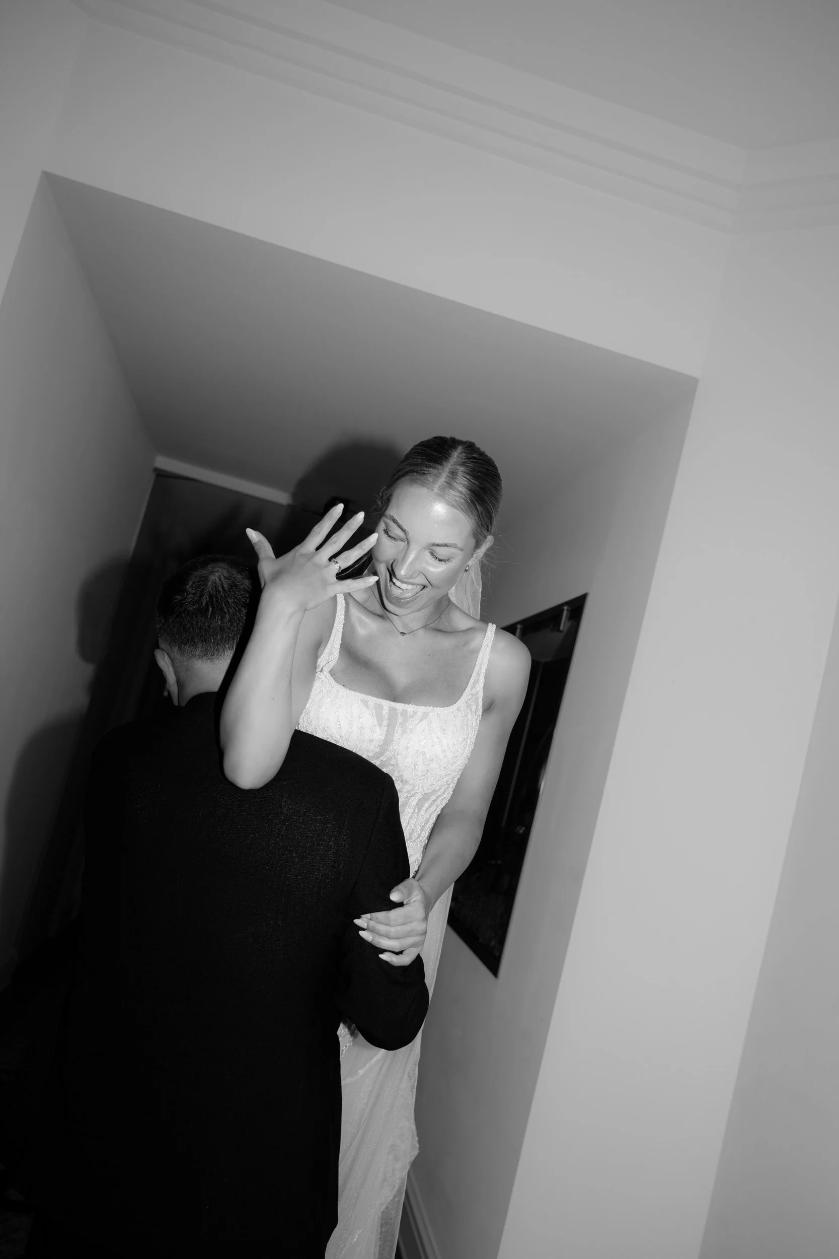 Editorial Brautpaarshooting nach der Trauung im Hotelflur des Hotel Atlantic Hamburg. Eine lachende Braut zeigt ihren Ring. Dokumentarische Hochzeitsfotografie von Valeska Weddings.