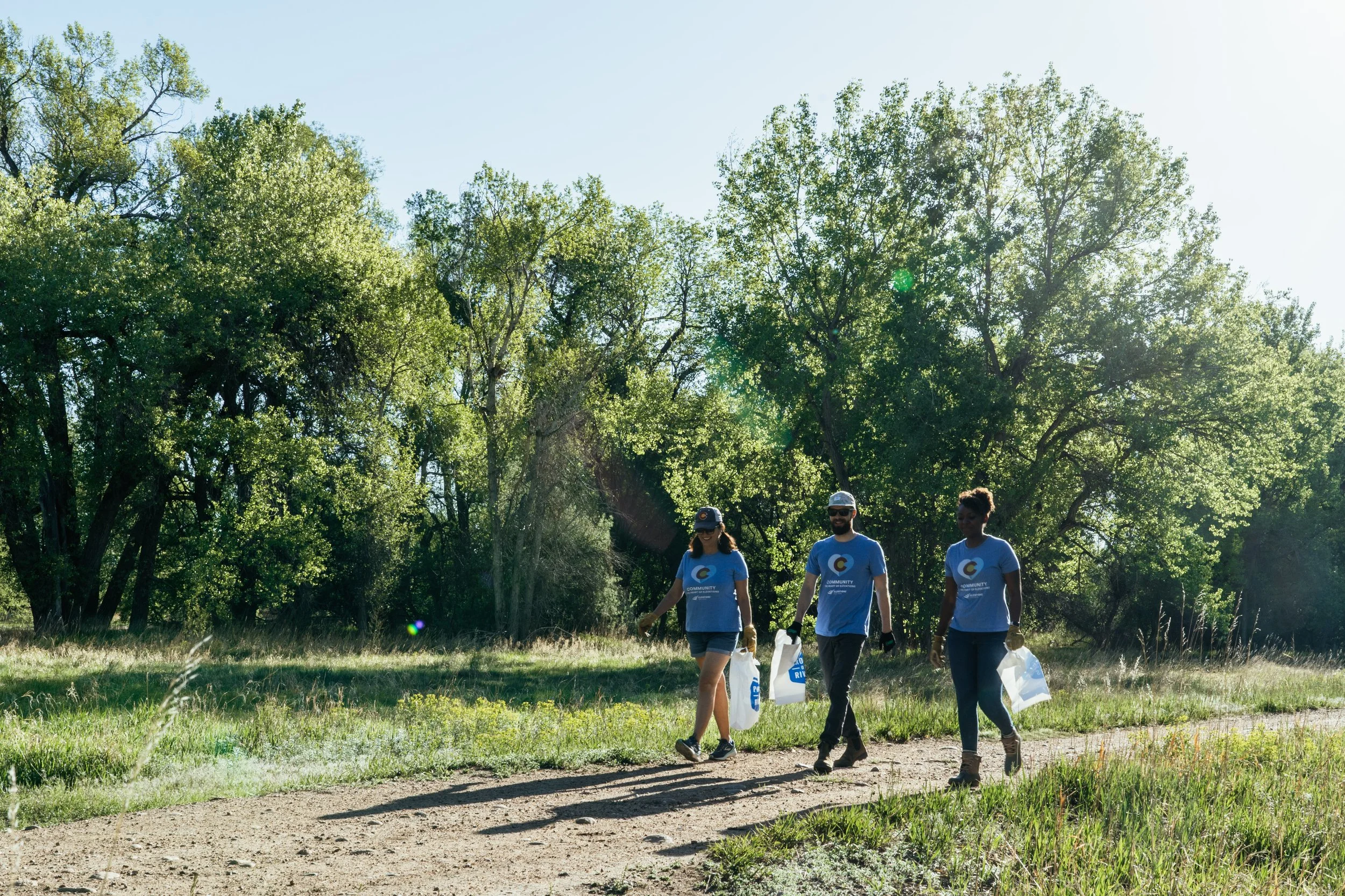 three people walking with blue shirts for a trash pickup