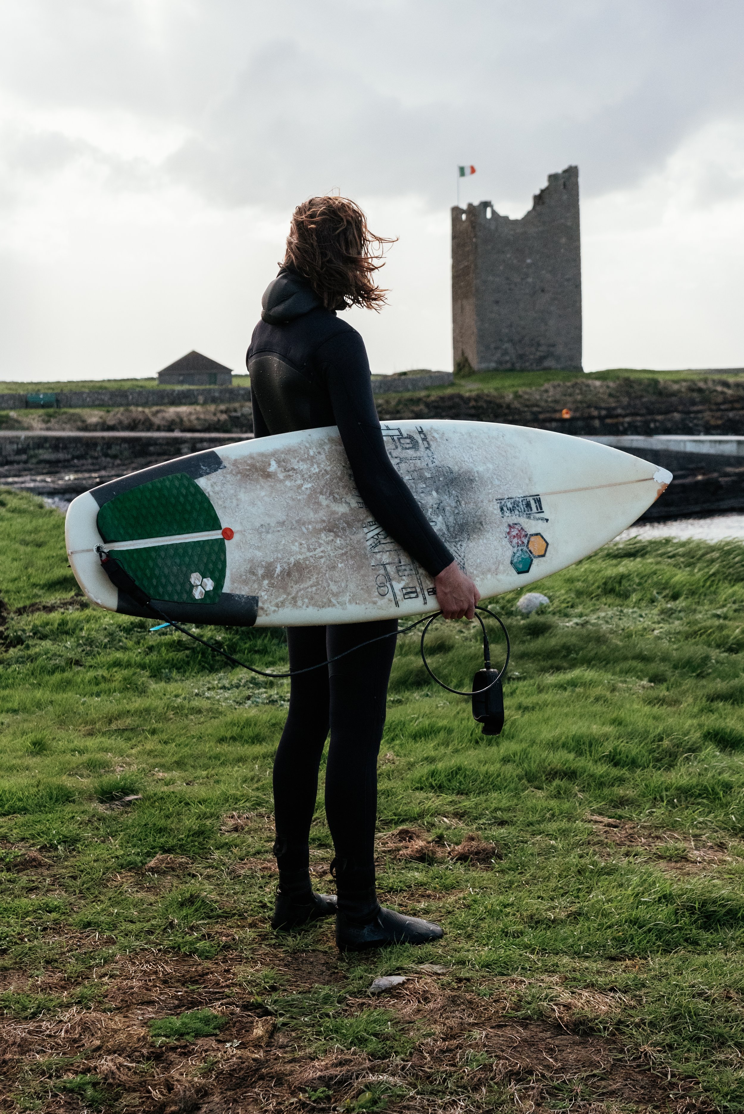 surfer holding a surfboard and looking at the ocean in ireland