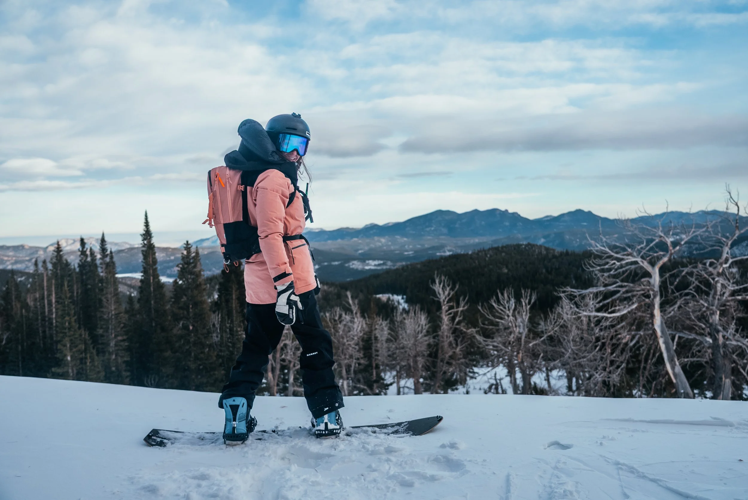 Cail Soria posing in the mountains before dropping in on her snowboard