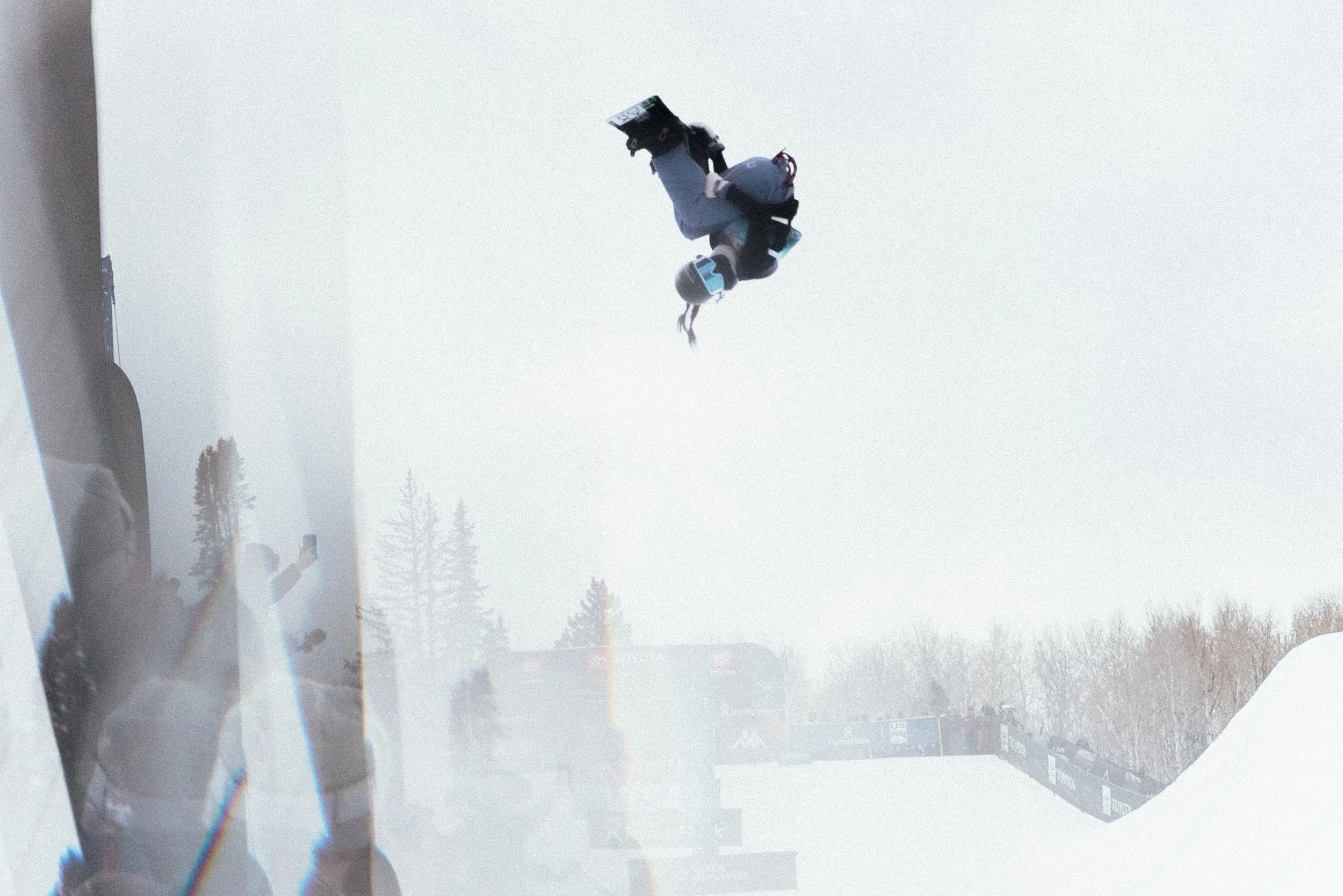 Olympic snowboarder Chloe Kim upside down above the halfpipe in Aspen, Colorado