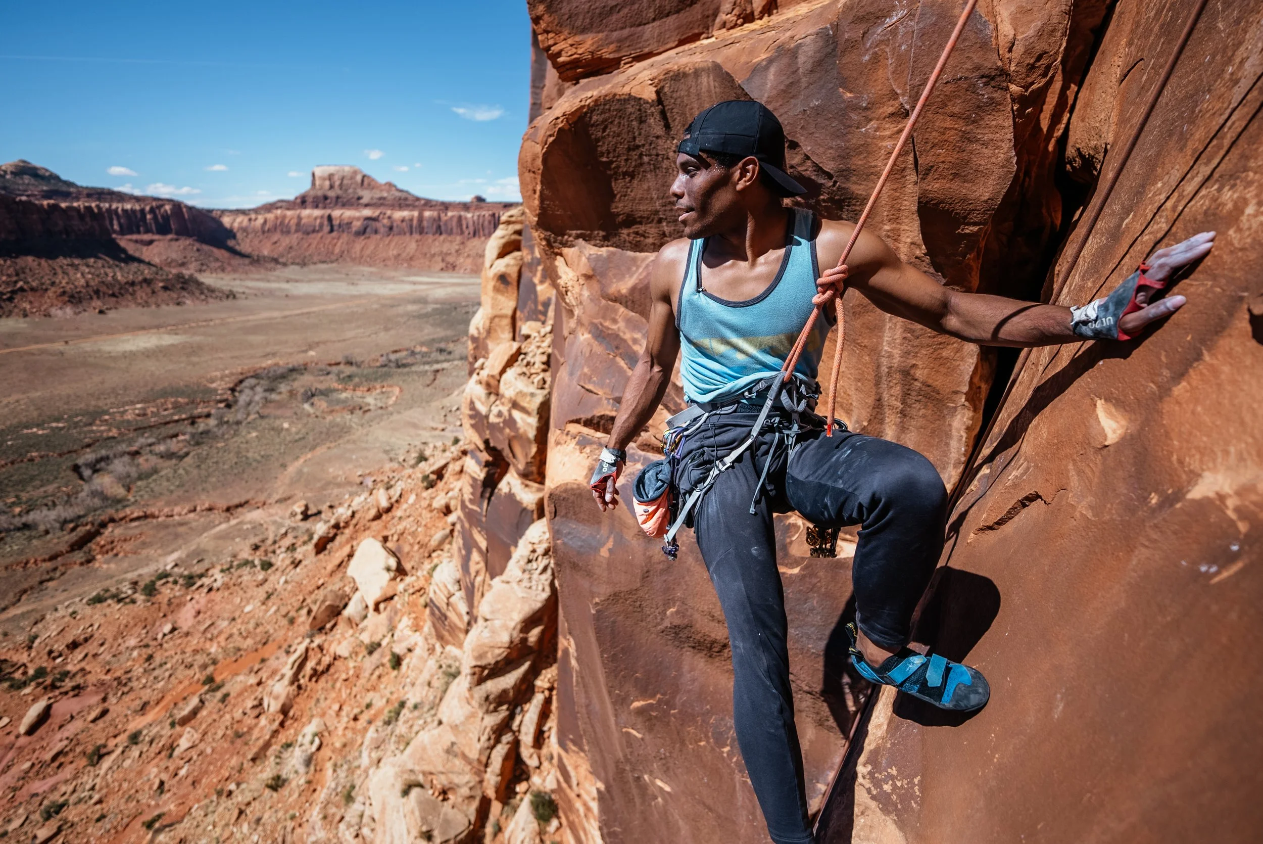 man in blue tanktop rock climbing in utah
