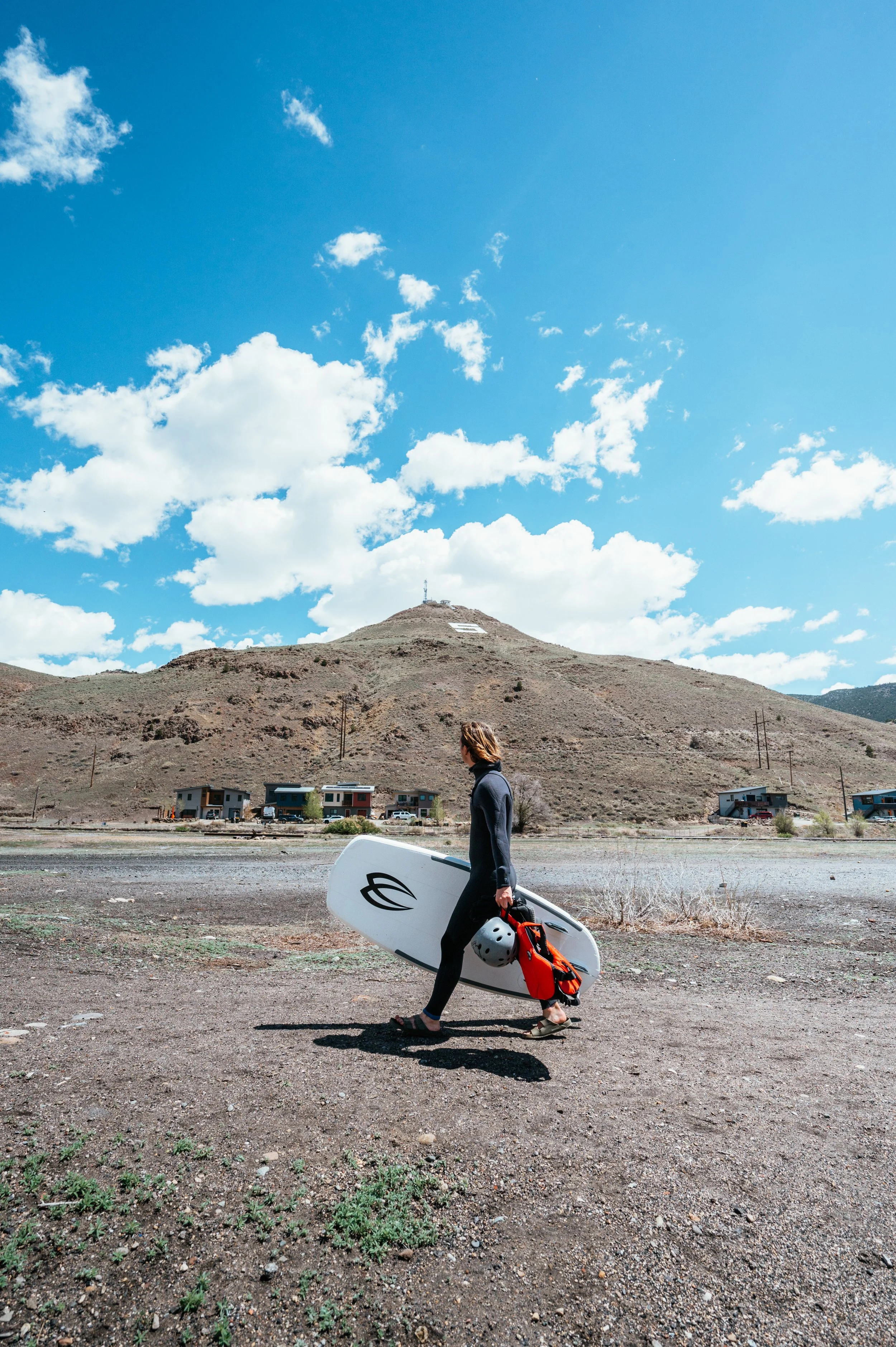 Roo Smith walking with surfboard in Colorado