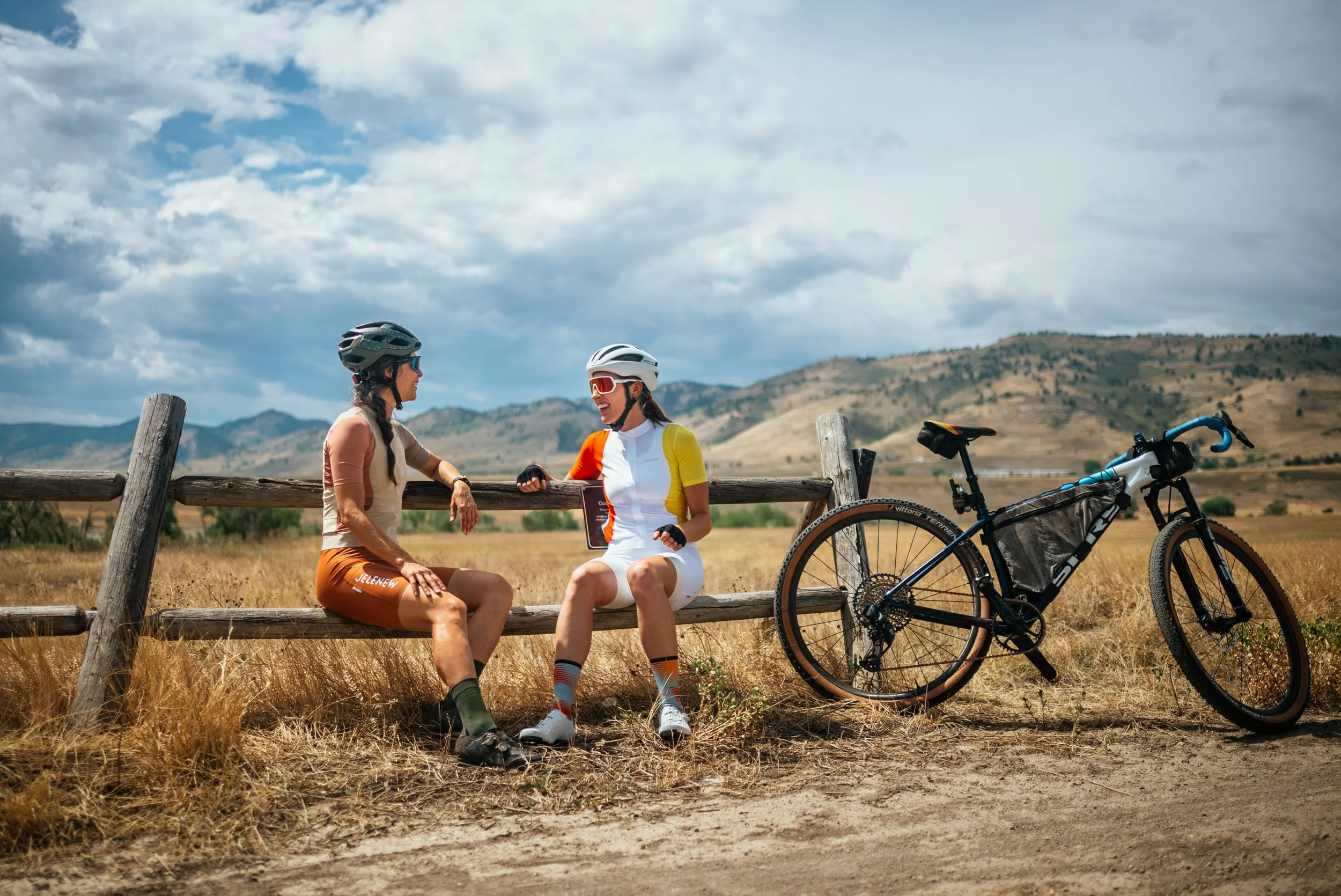two cyclists sitting on a bench and talking