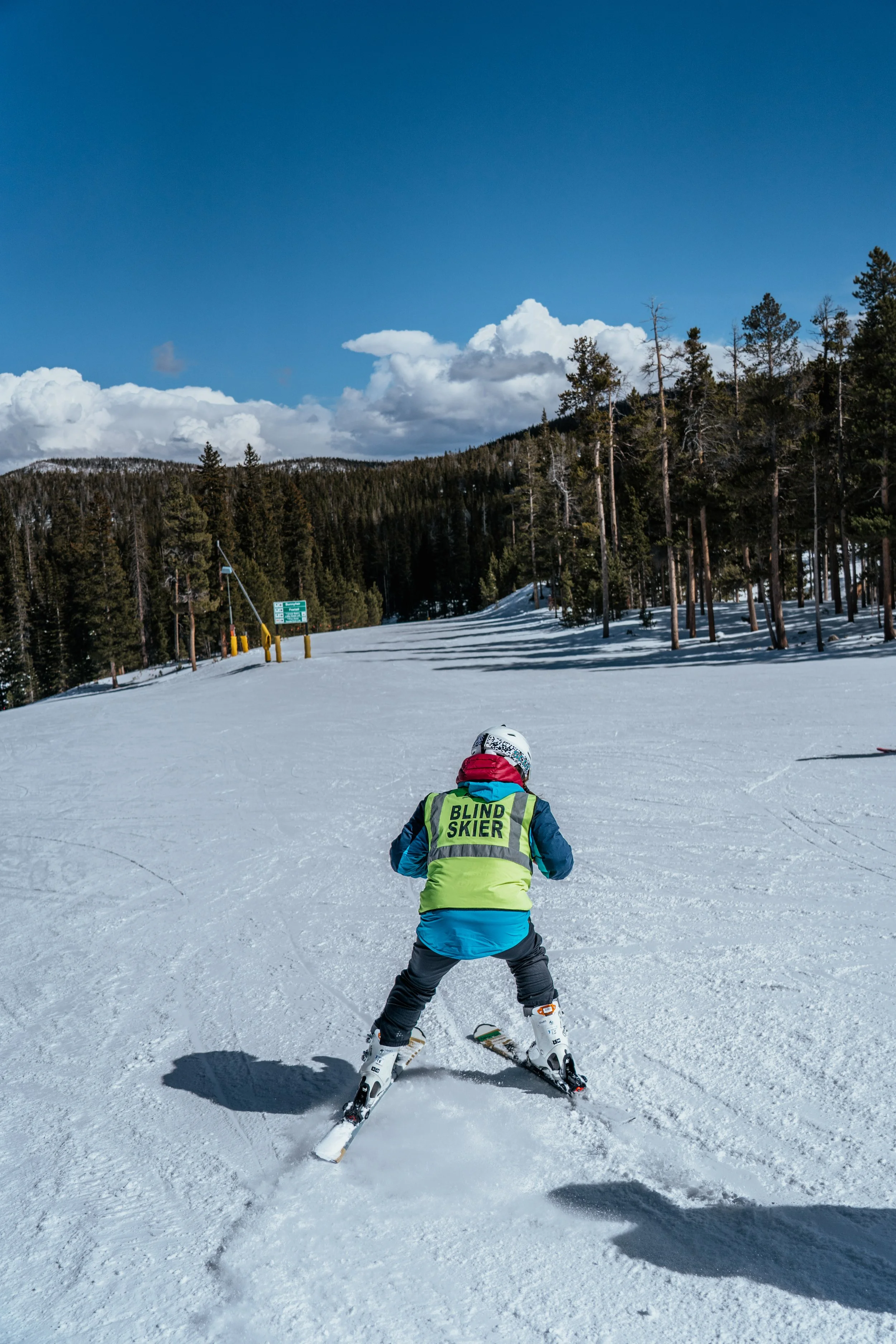 A blind skier descends down Eldora Ski Resort on a sunny day