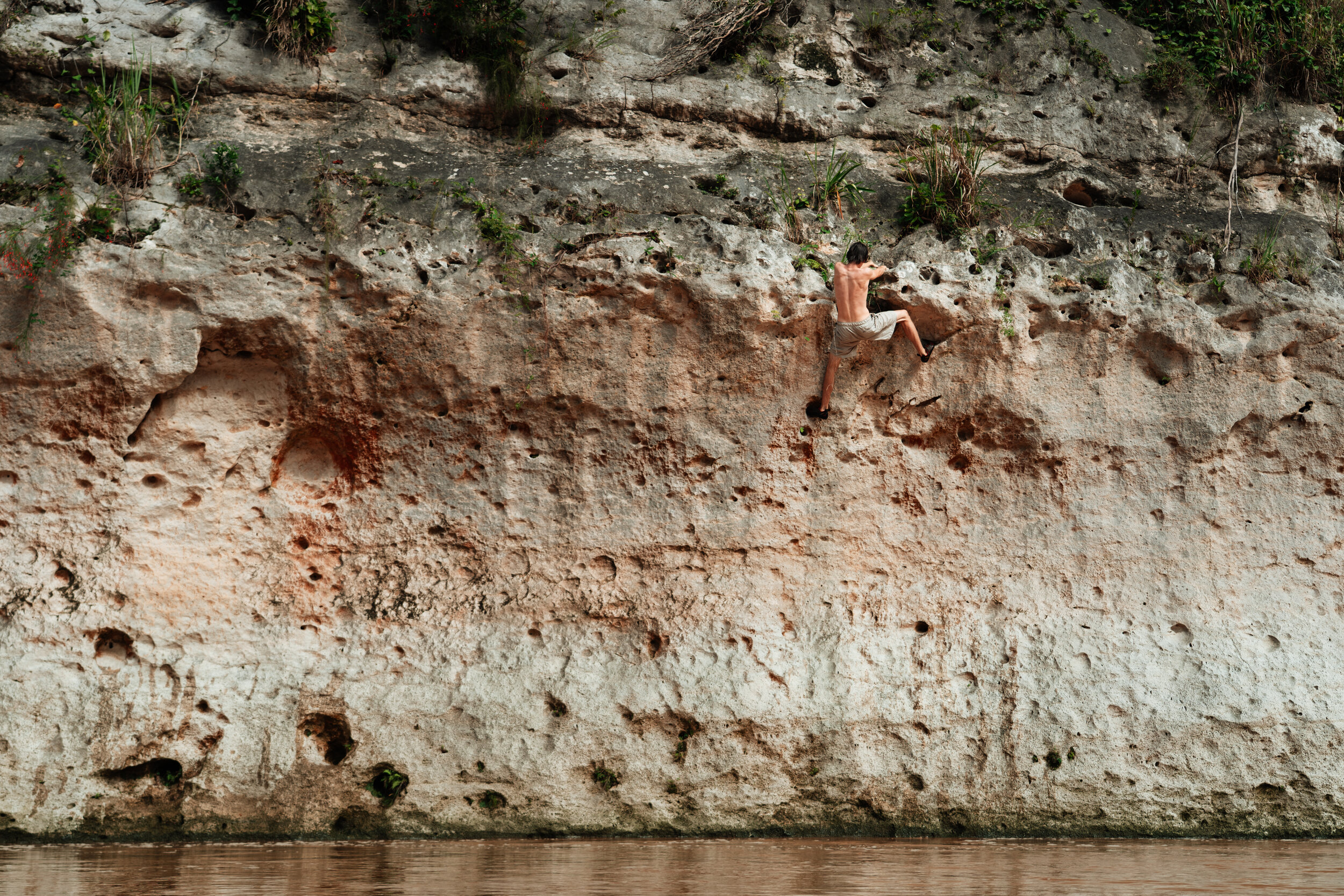 A man climbing a rock face near a body of water.