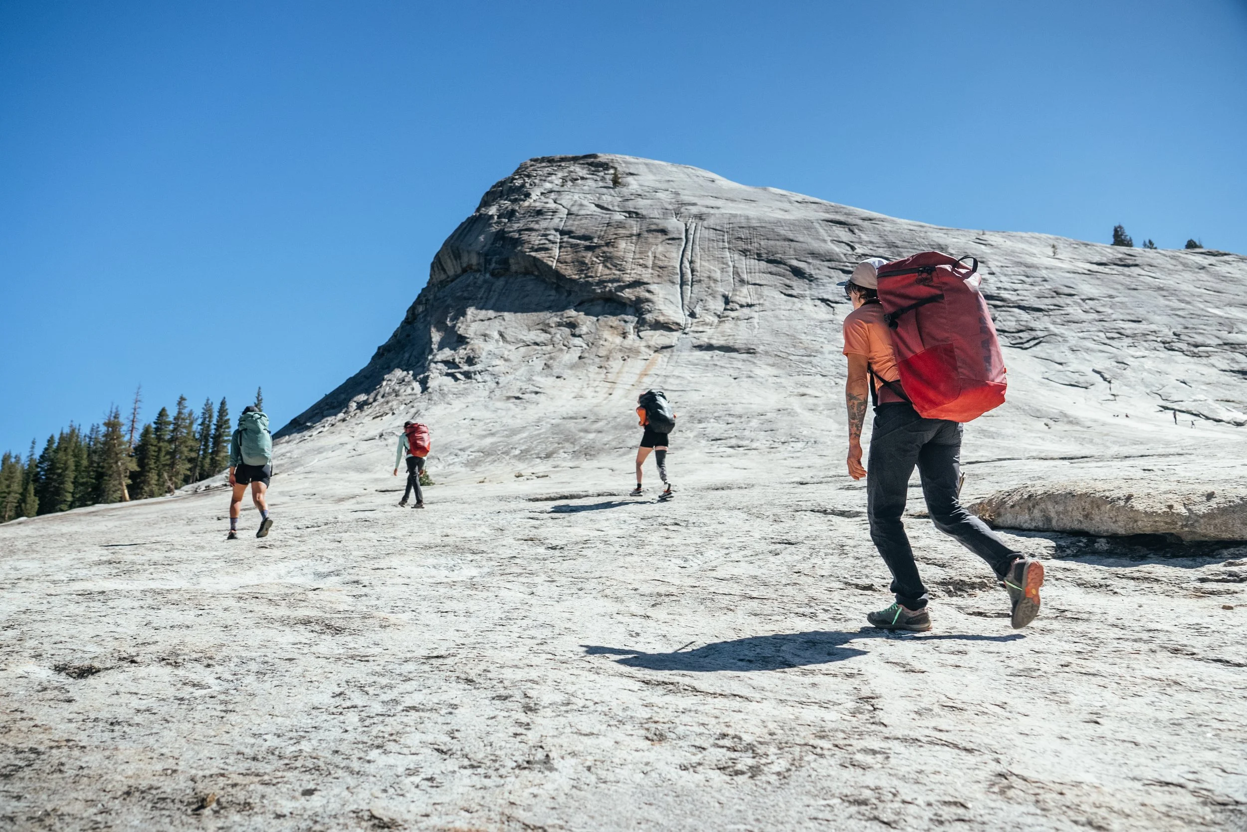 the athletes walking to the base of a giant granite dome in Yosemite