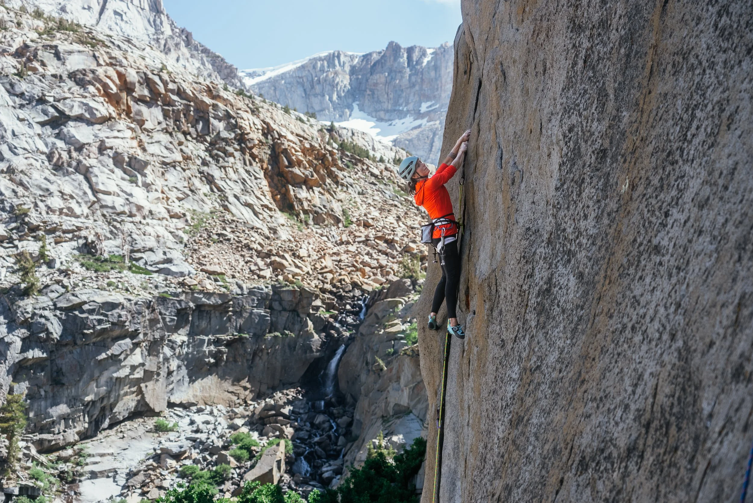 A rock climber in a red coat climbing near Yosemite