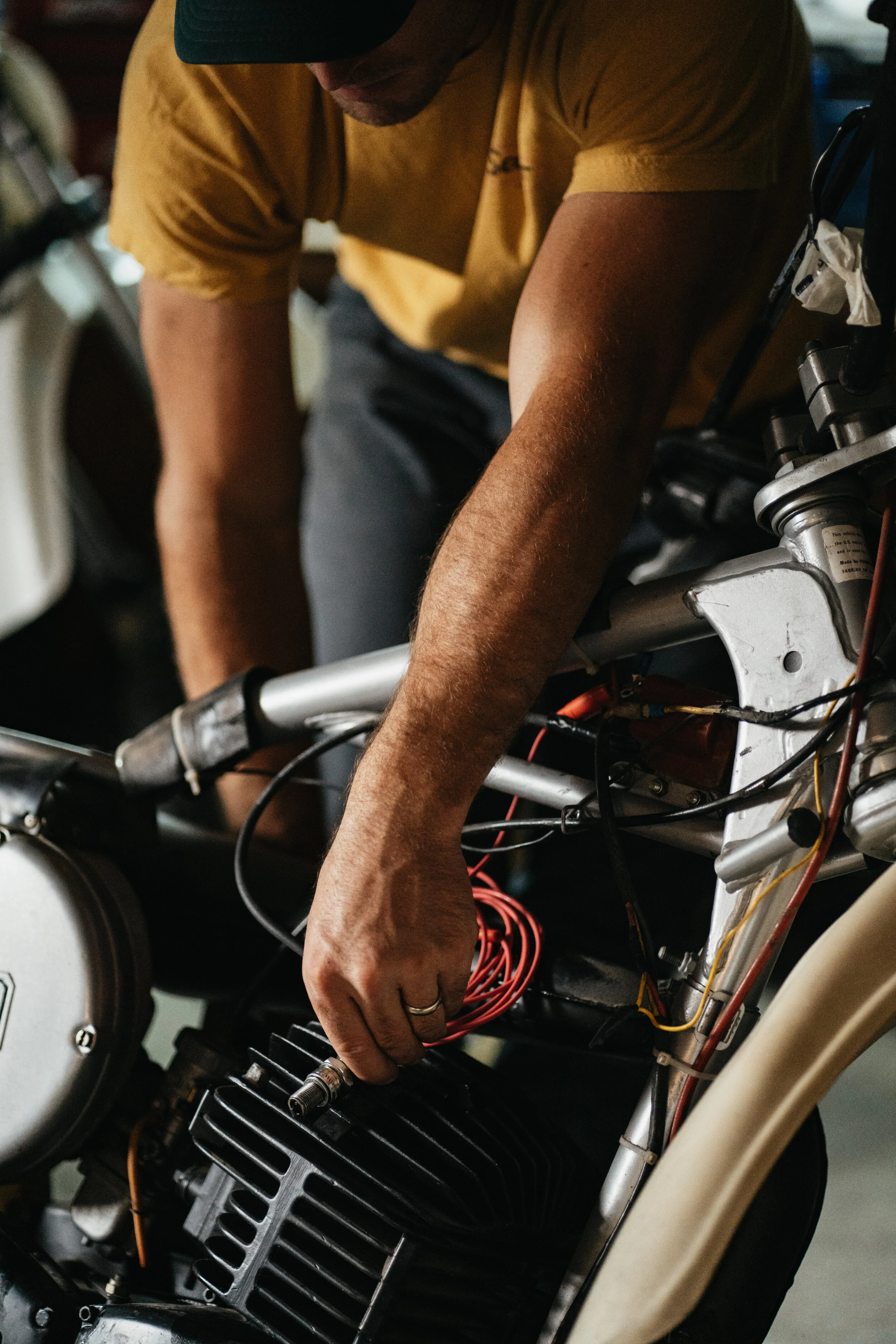 A person working on the wiring of a motorcycle in a garage or workshop.