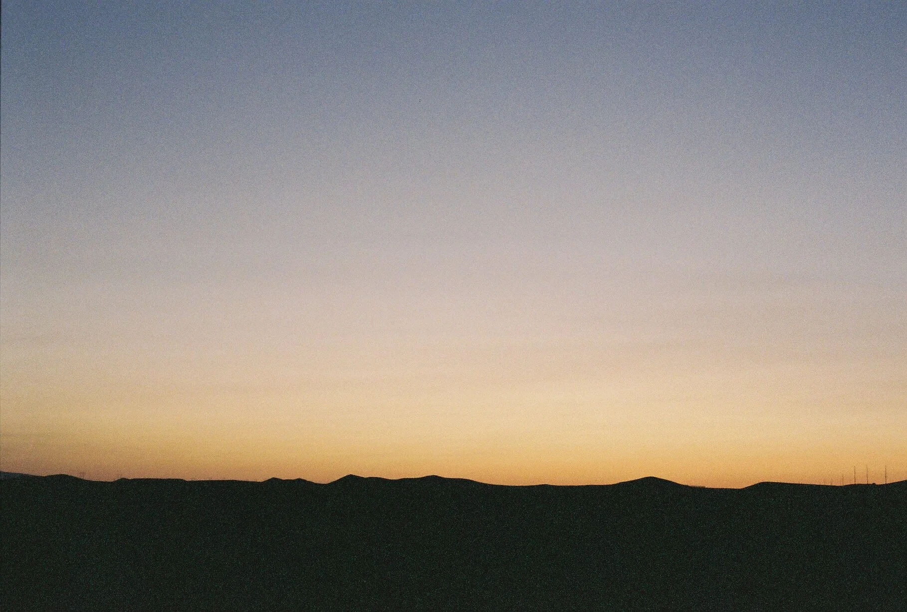 Sunset over rolling hills with a colorful sky.