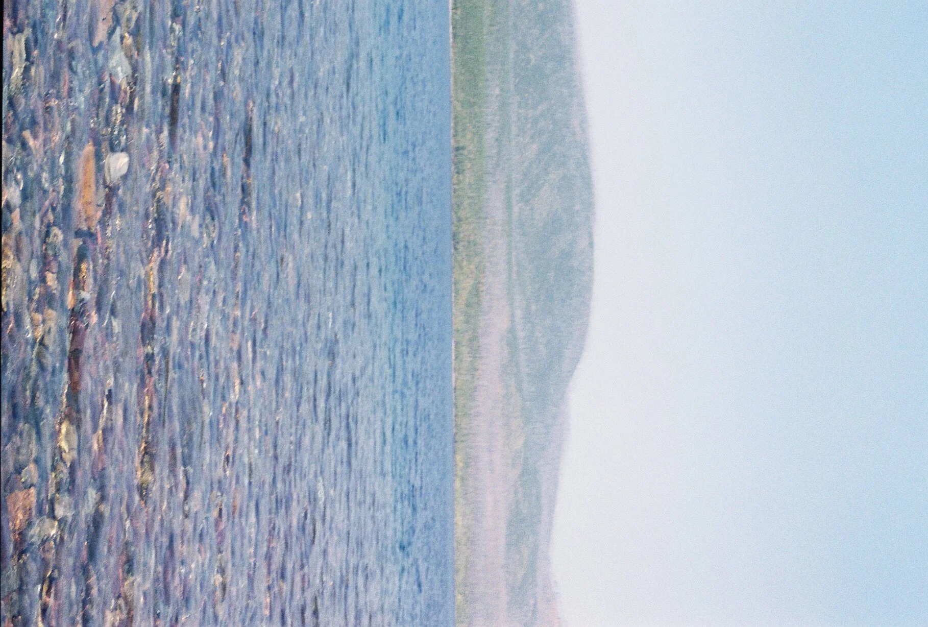 A foggy landscape with a river in the foreground and hills in the background.