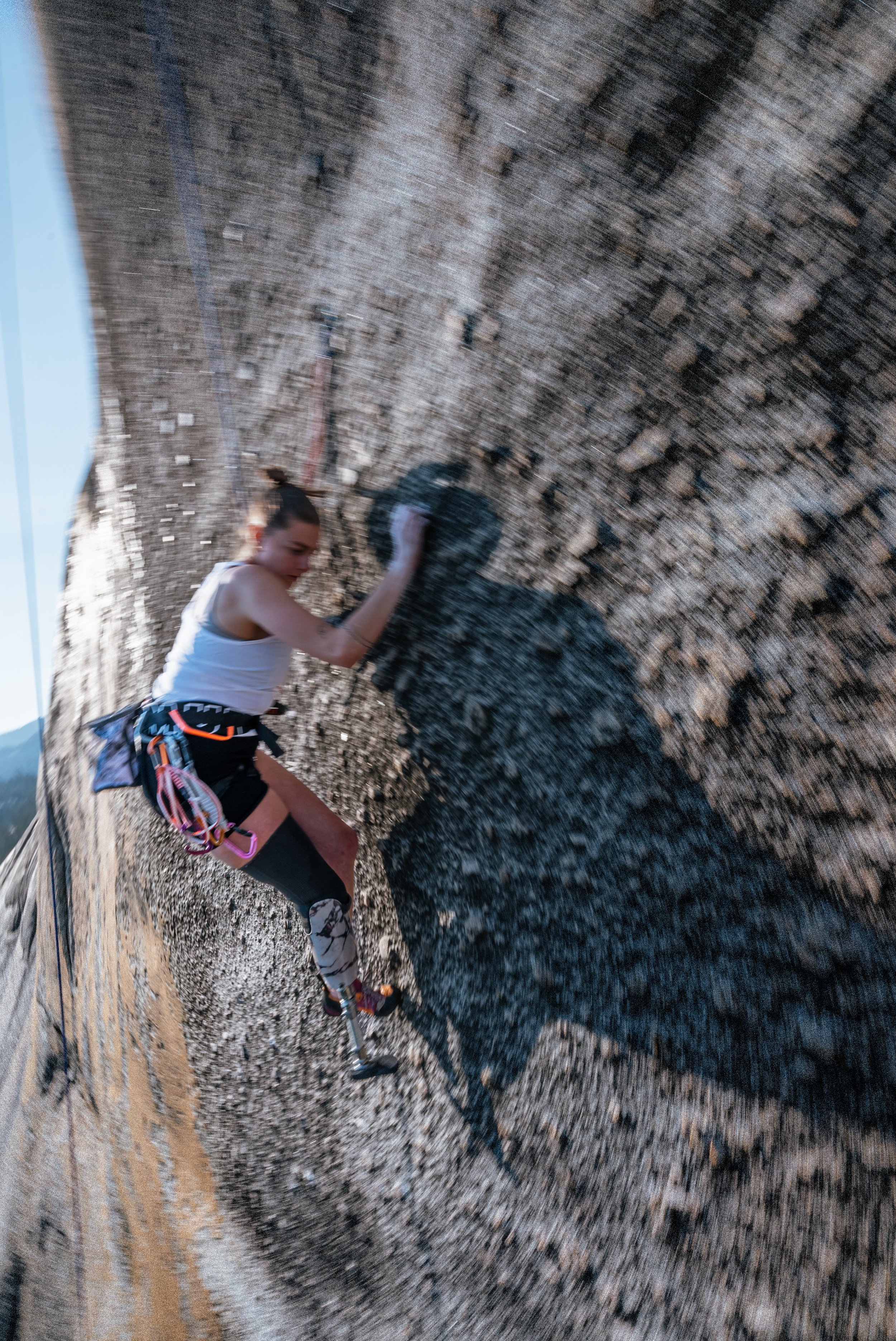 A woman rock climbing on a vertical wall with a rough, textured surface.