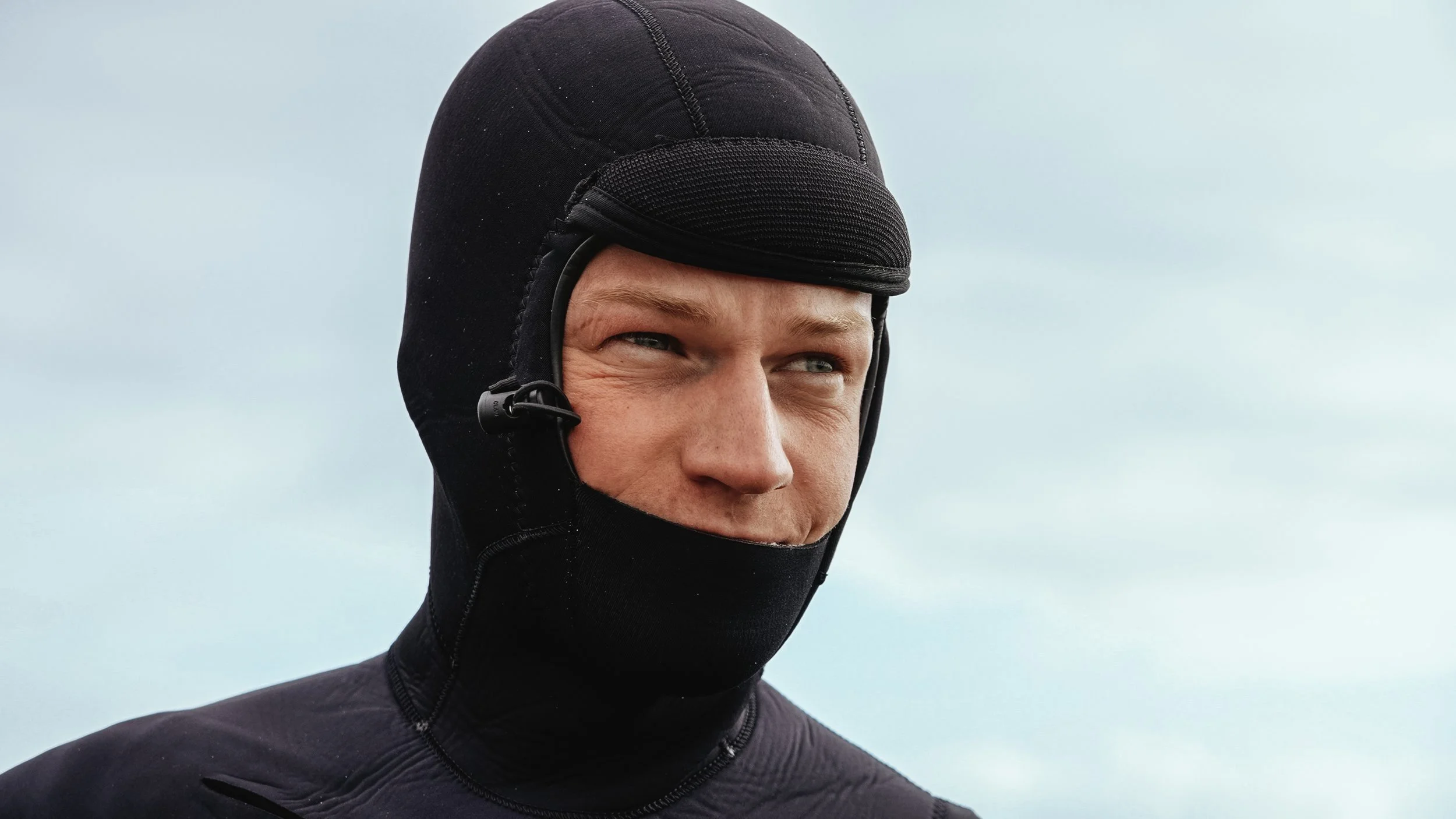 A man wearing a black ski mask and jacket outdoors.