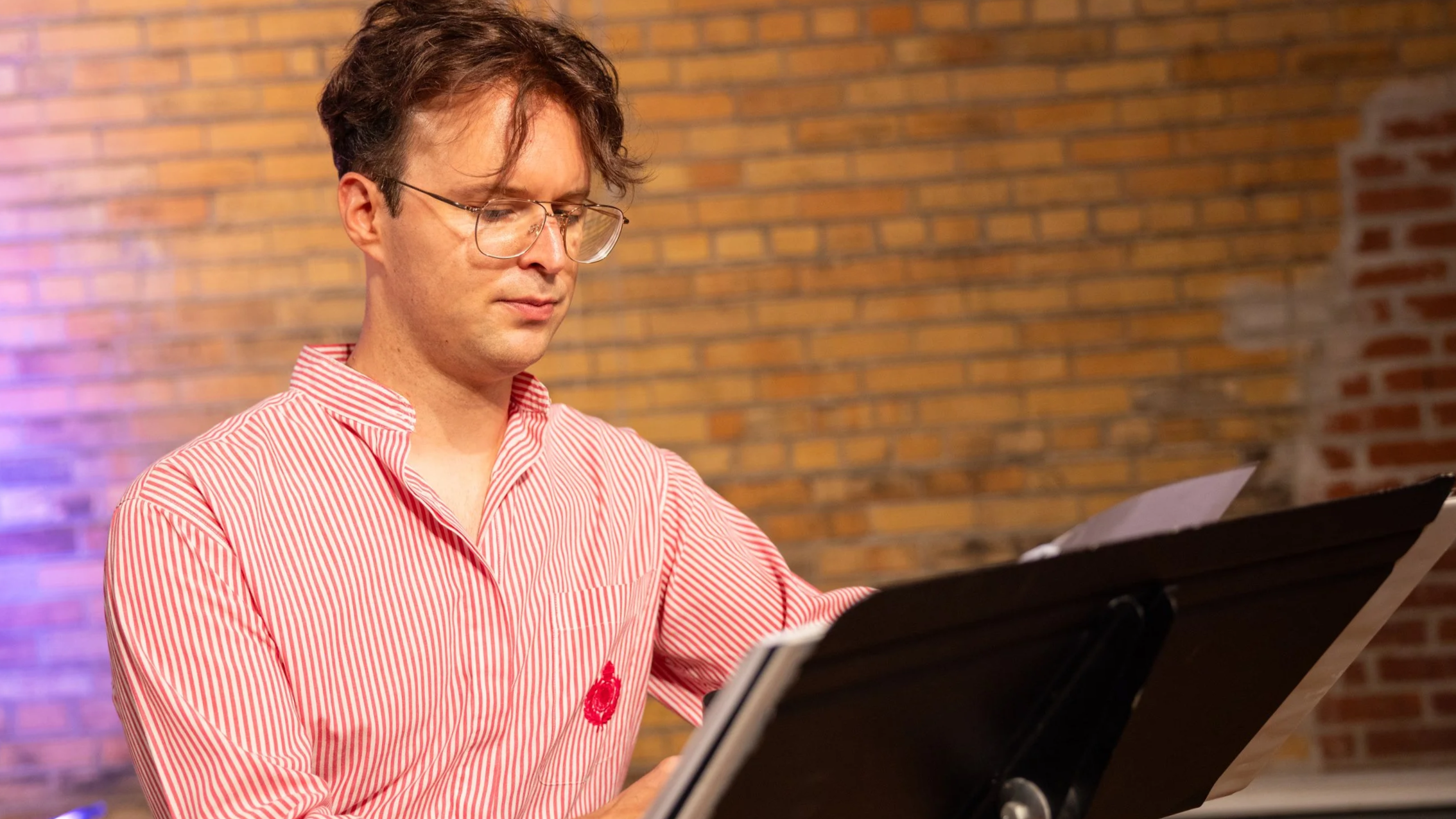Man looks at sheet music on a music stand.