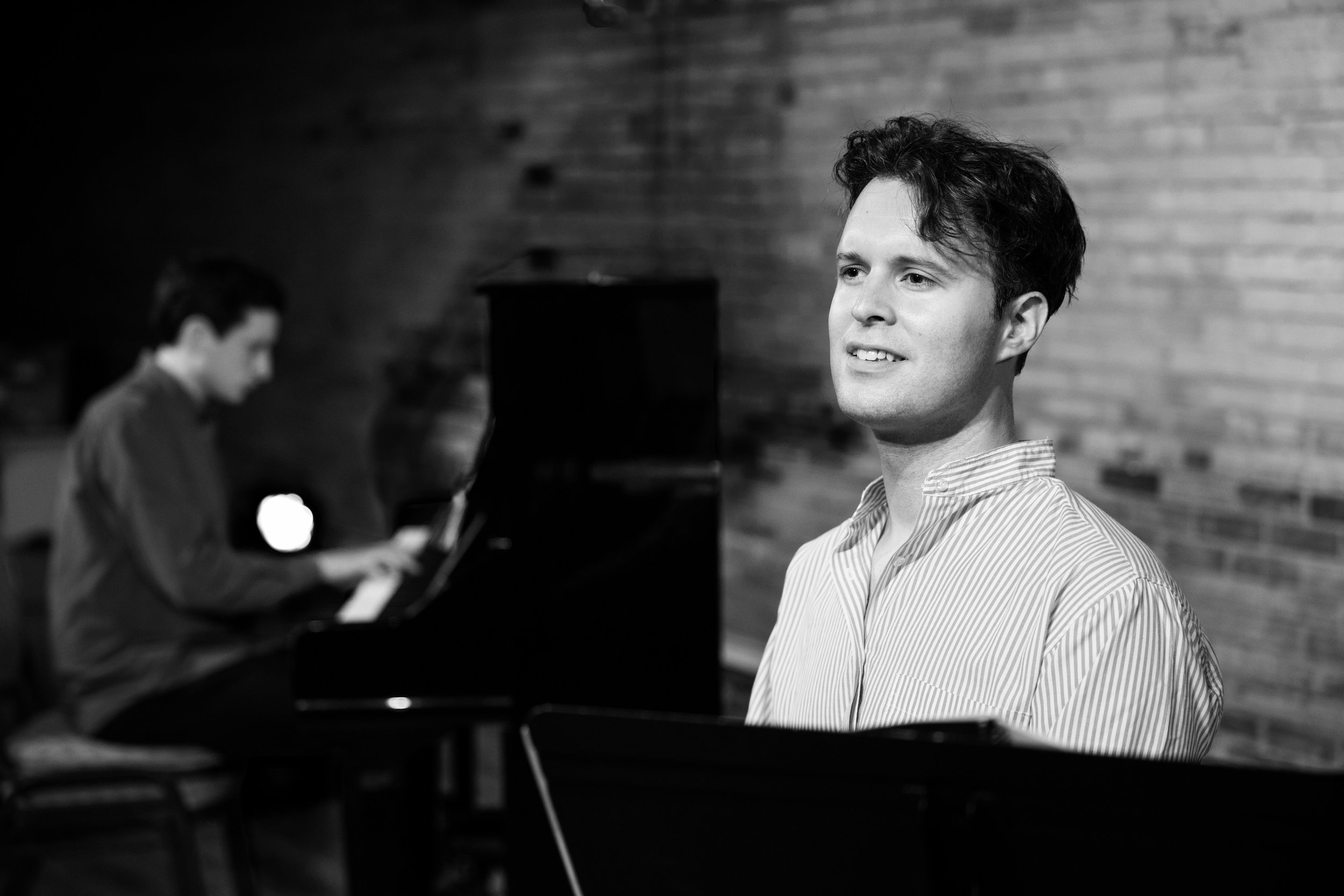 Man looking into the distance while accompanist plays in the background.
