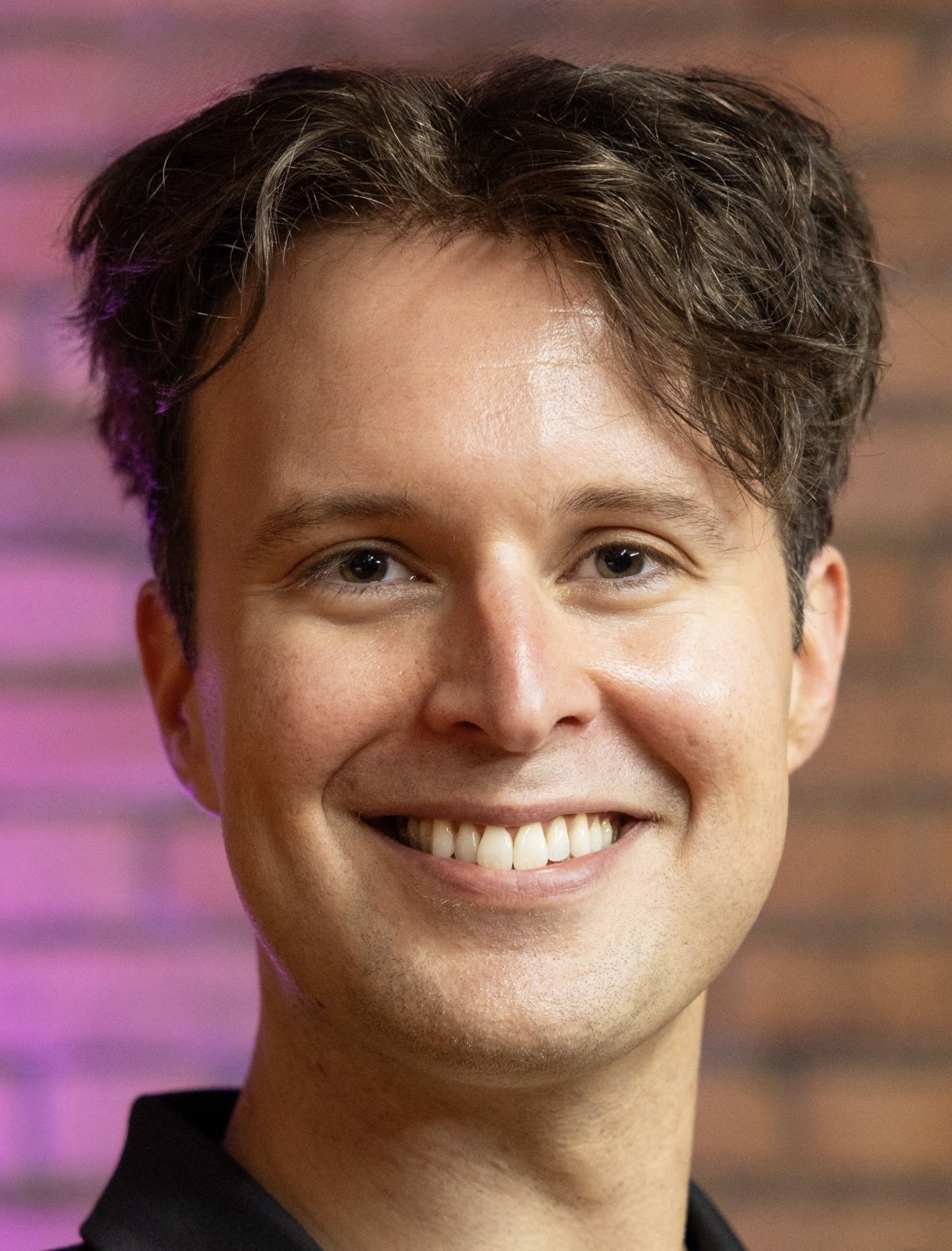 Man smiling in front of brick background