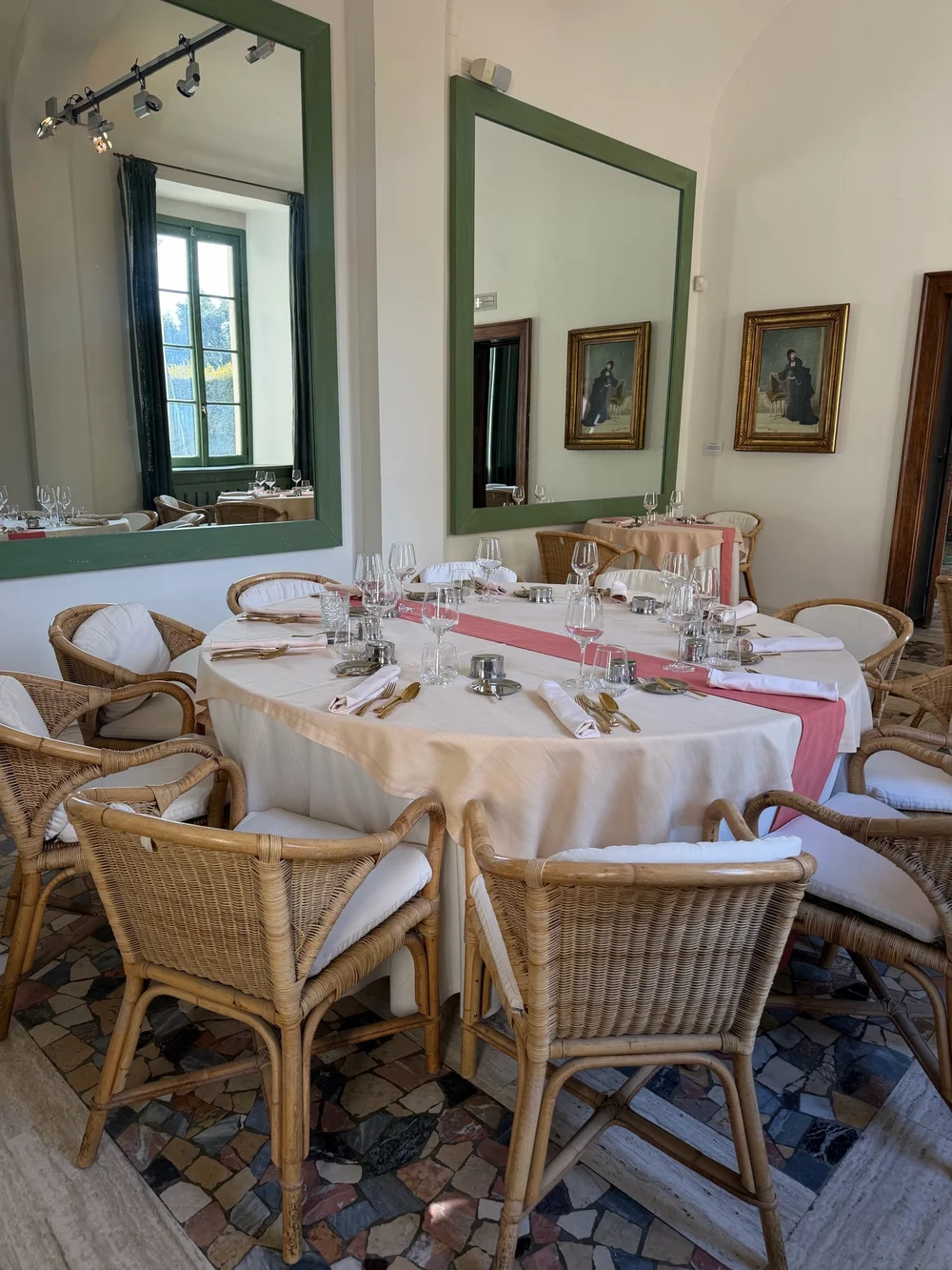 La sala del ristorante Luce dentro Villa Panza, con la tavola apparecchiata, le sedie in vimini e i grandi specchi