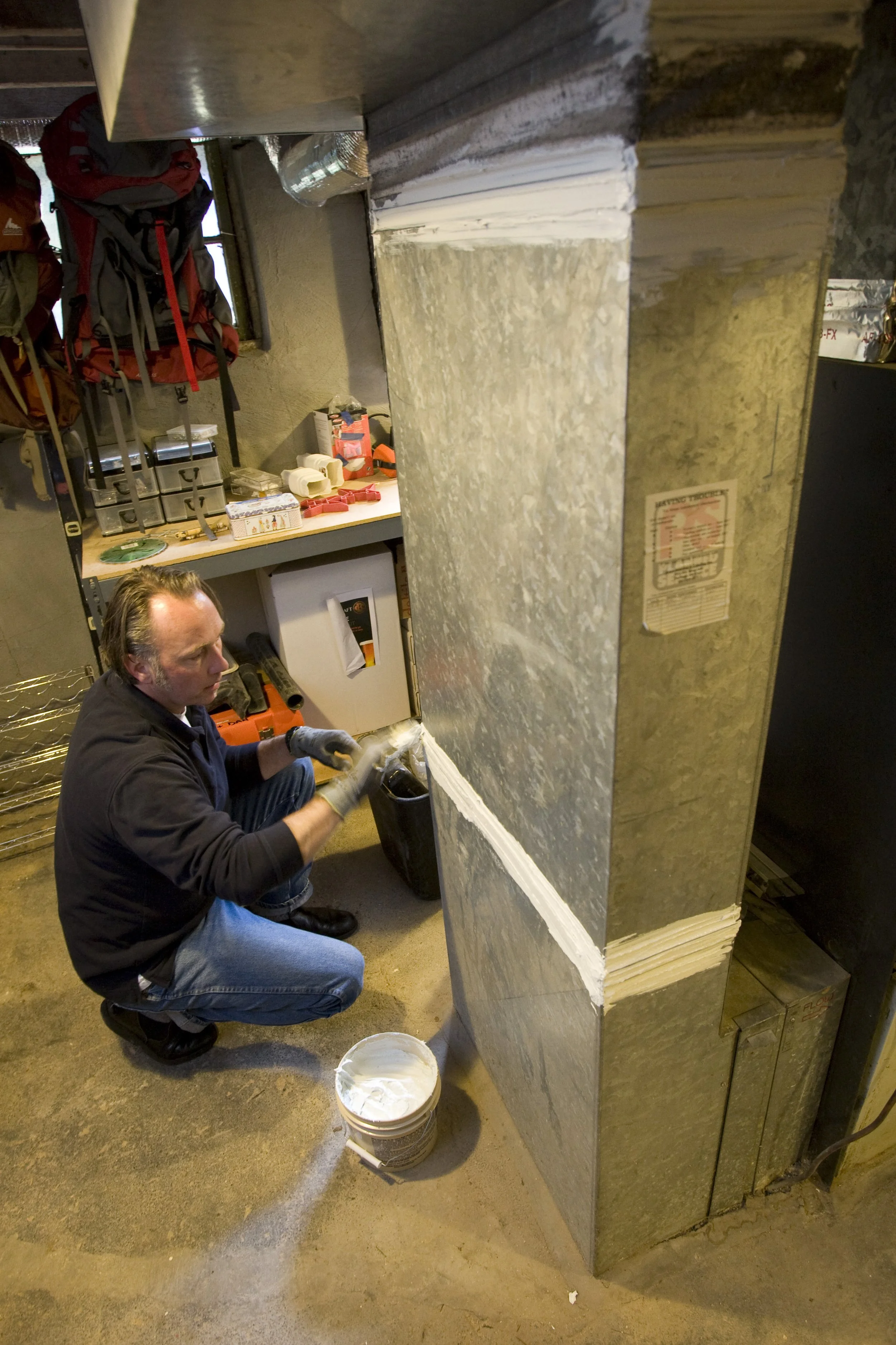 A contractor applies a sealant on the gaps between metal venting pieces.