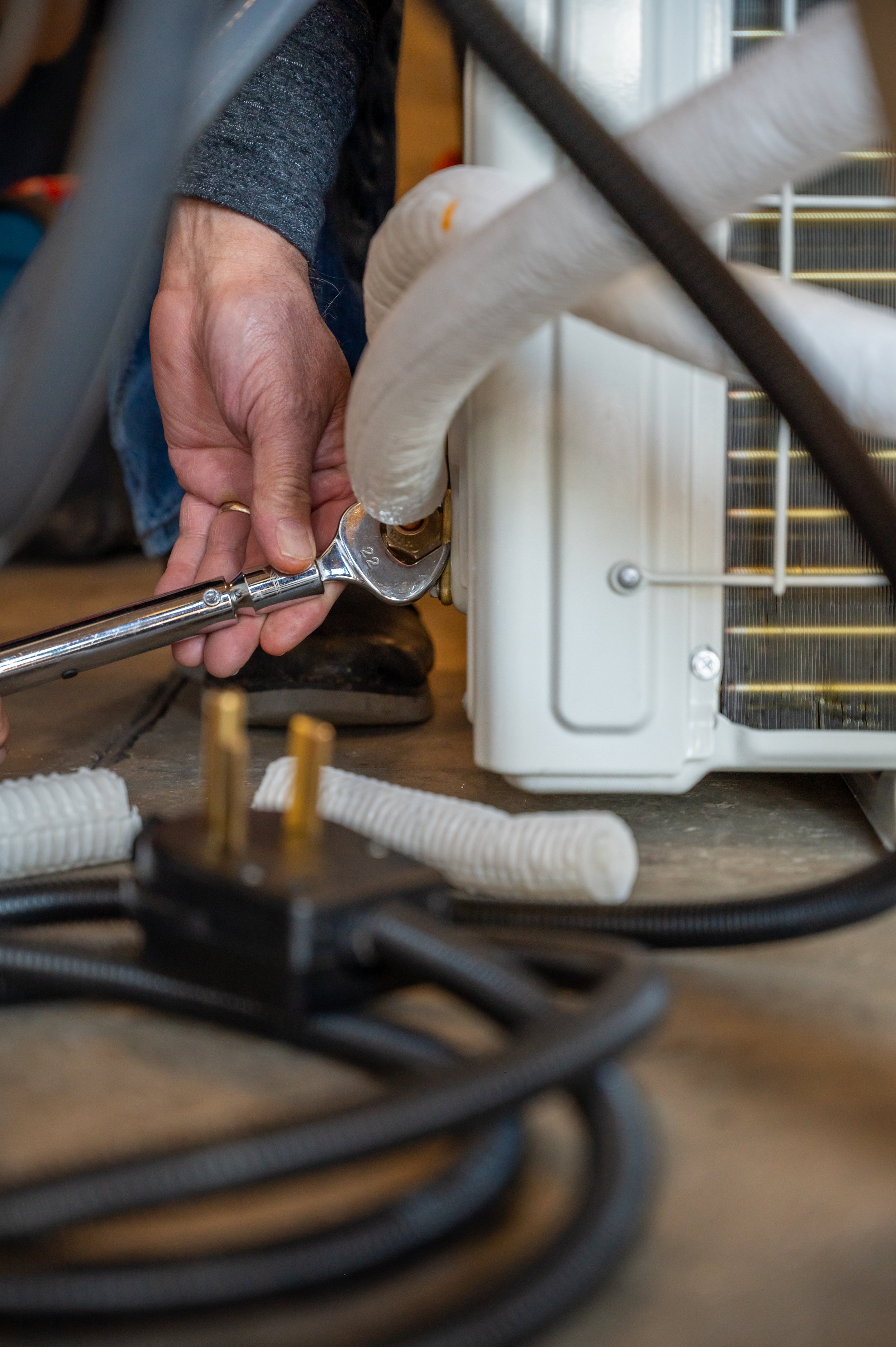 A closeup photo of hands using a wrench to tighten a connection.