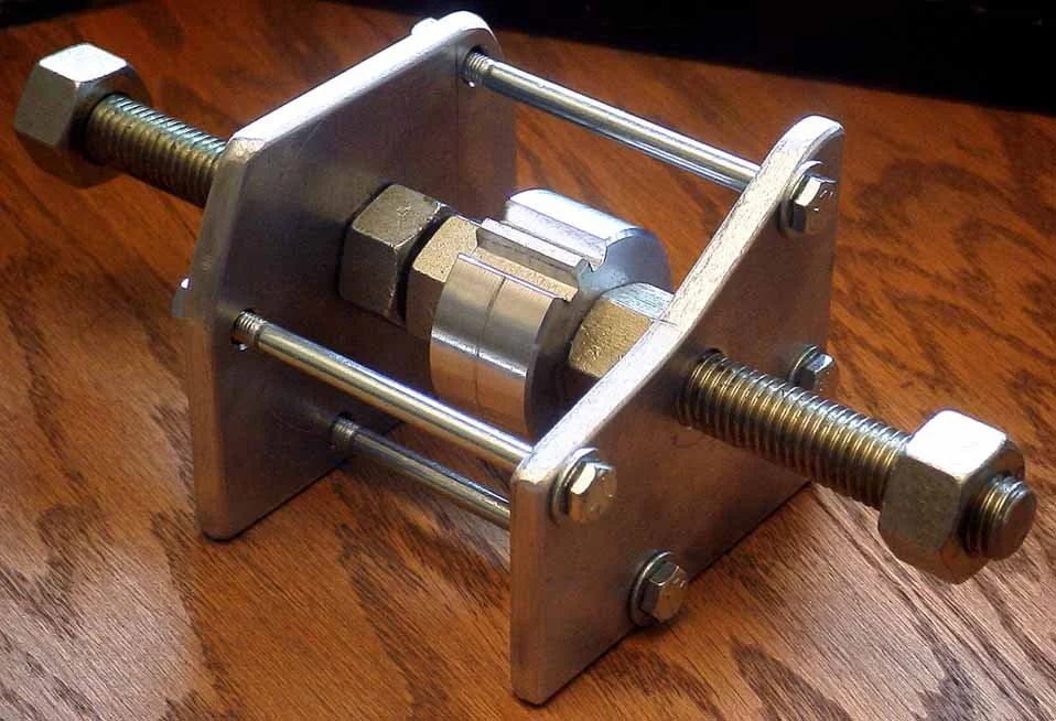 Photo 4:  This blocking tool may be used in place of the starting motor to keep the flywheel from spinning when removing the starting dog nut. It is designed to be used with the long starter bolts if the oil sump is fitted.  When the oil sump is off,