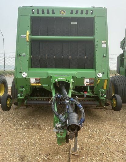 Front view of a green John Deere agricultural implement with a black central component and attached hydraulic hoses.