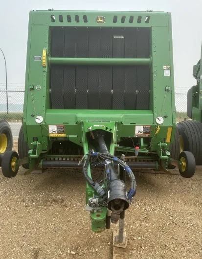 Front view of a large green John Deere agricultural baler, showing its black bale chamber and towing hitch.