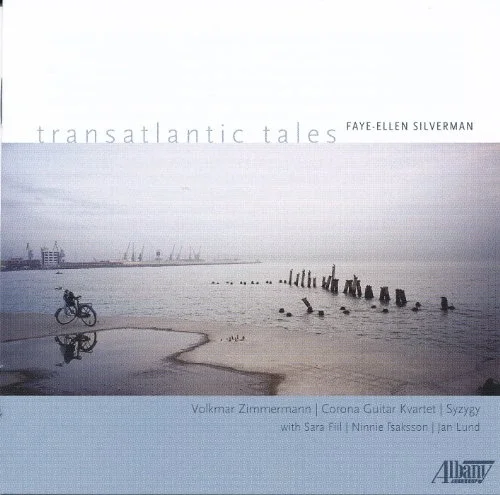 Cover album featuring a seascape with a bicycle leaning on a rail along the shoreline, wooden pilings in the water, and a distant industrial area with cranes and buildings. The sky is overcast.