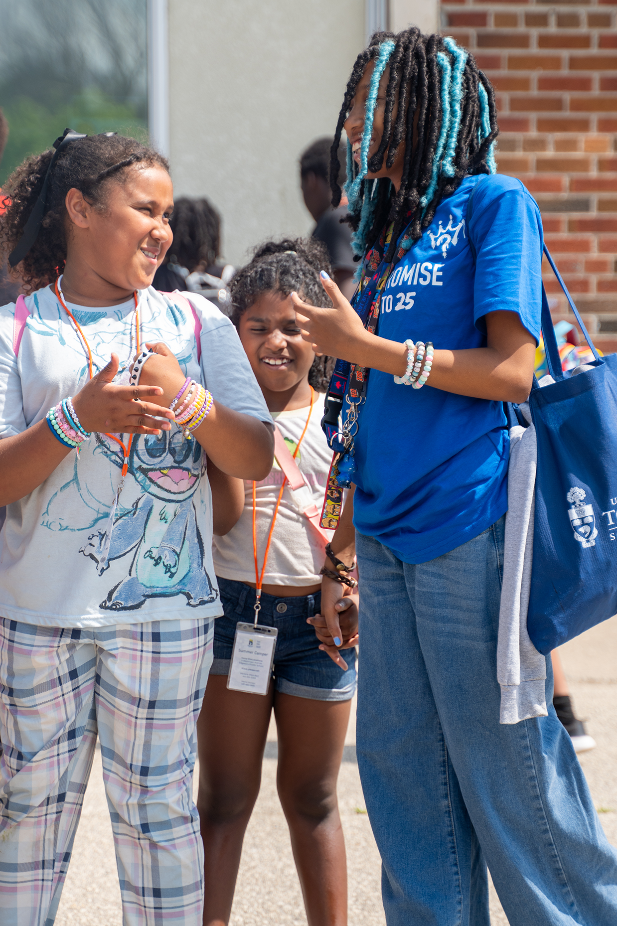 Group of children and a woman outside talking and smiling