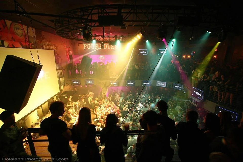 Inside a lively nightclub with colorful lights and a large crowd dancing and socializing.