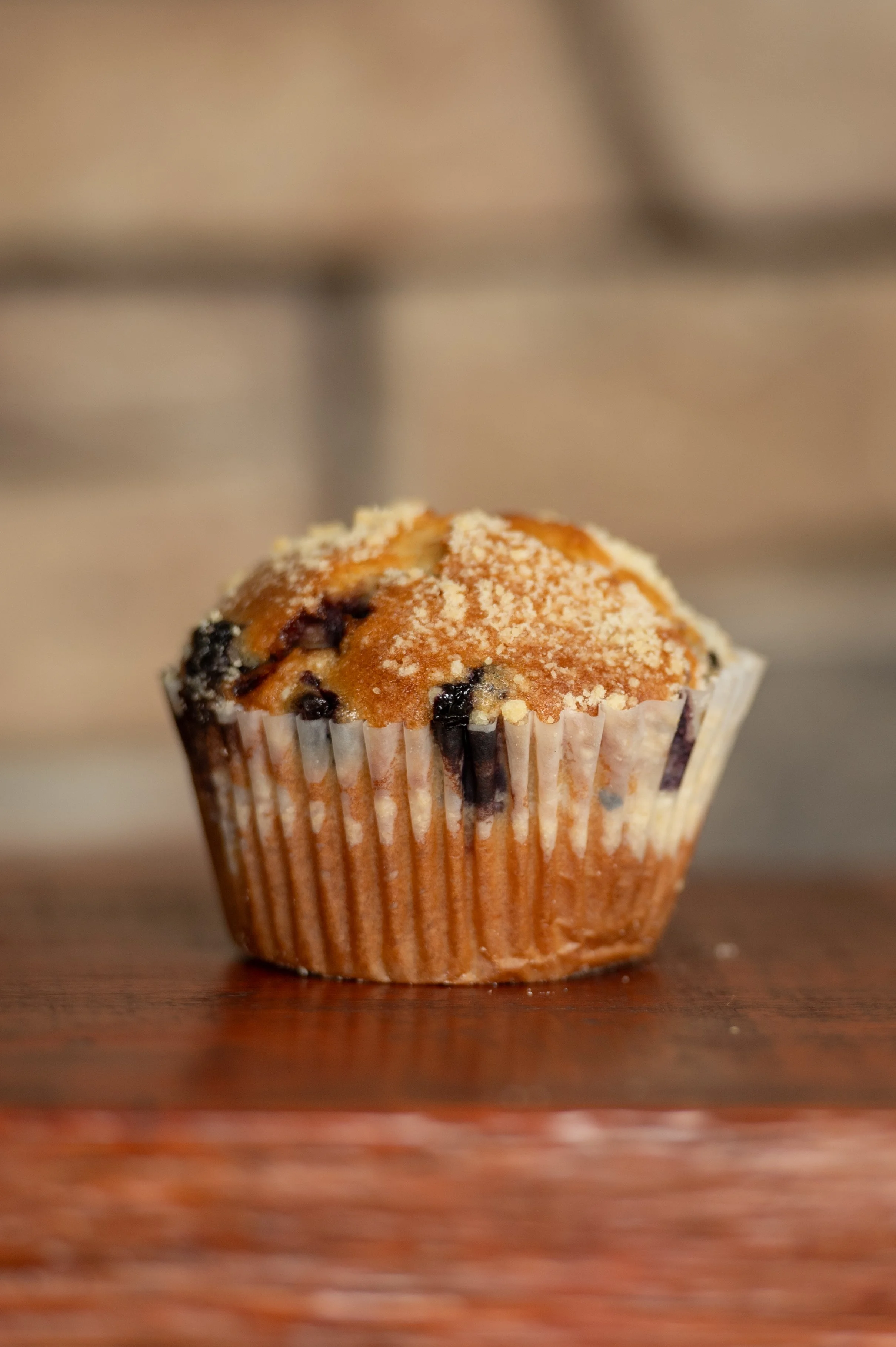 Close-up of a blueberry muffin with powdered sugar on top, placed on a wooden surface.