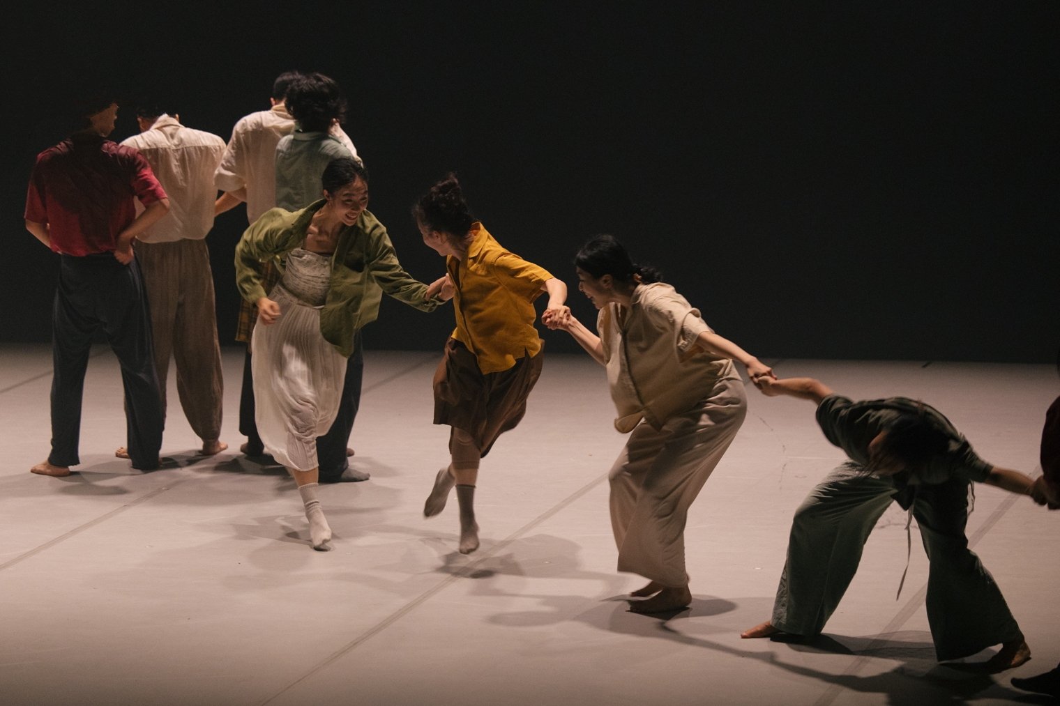 Group of people holding hands in a dance theater performance on stage. From the dance theatre production Flowers of Ruin.