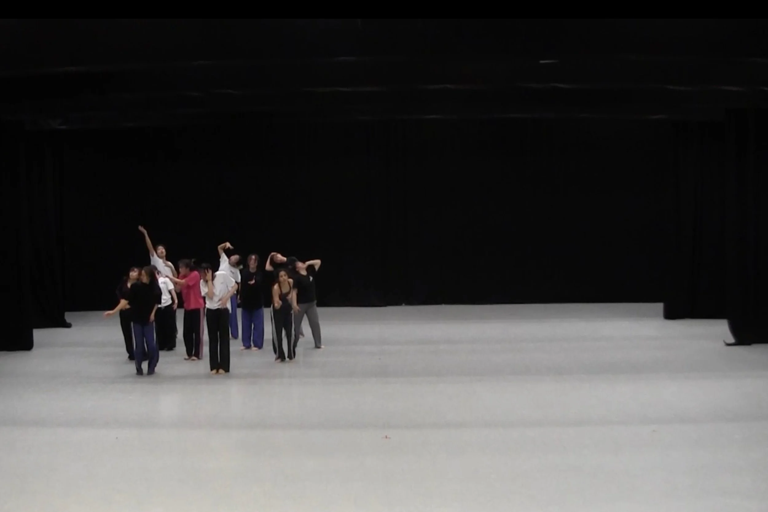 Group of dancers from Hong Kong Academy for Performing Arts performing on a stage with black curtains and a plain, light-colored floor. From the choreography WALLS.