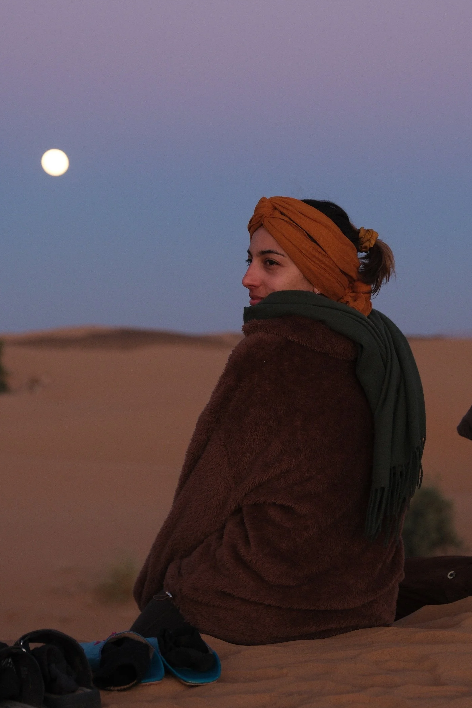 Joanna Riquett, retreat organizer, sitting on a dune at moonrise in the Sahara