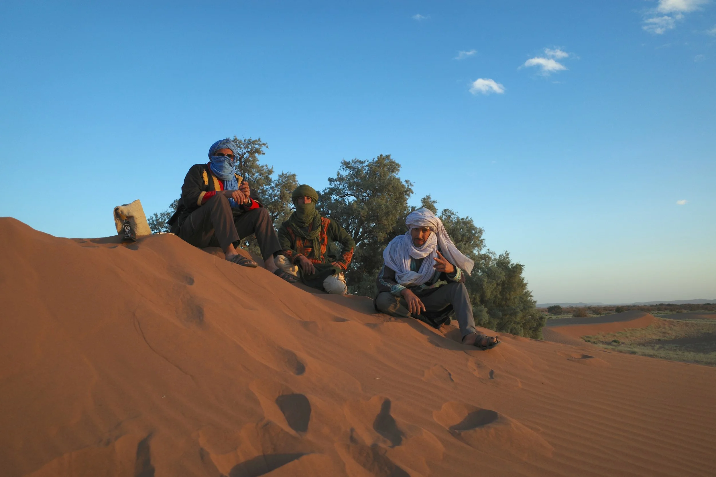 Désert et Montagne Maroc guides and walkers resting under a tree on a desert dune
