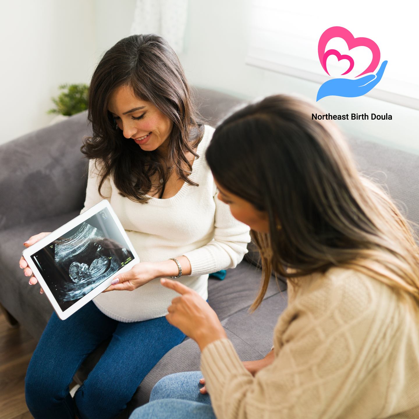 Pregnant lady image sitting with a female birth doula and both of them looking at a baby x ray
