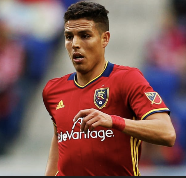 A soccer player in a red jersey running on the field during a match.