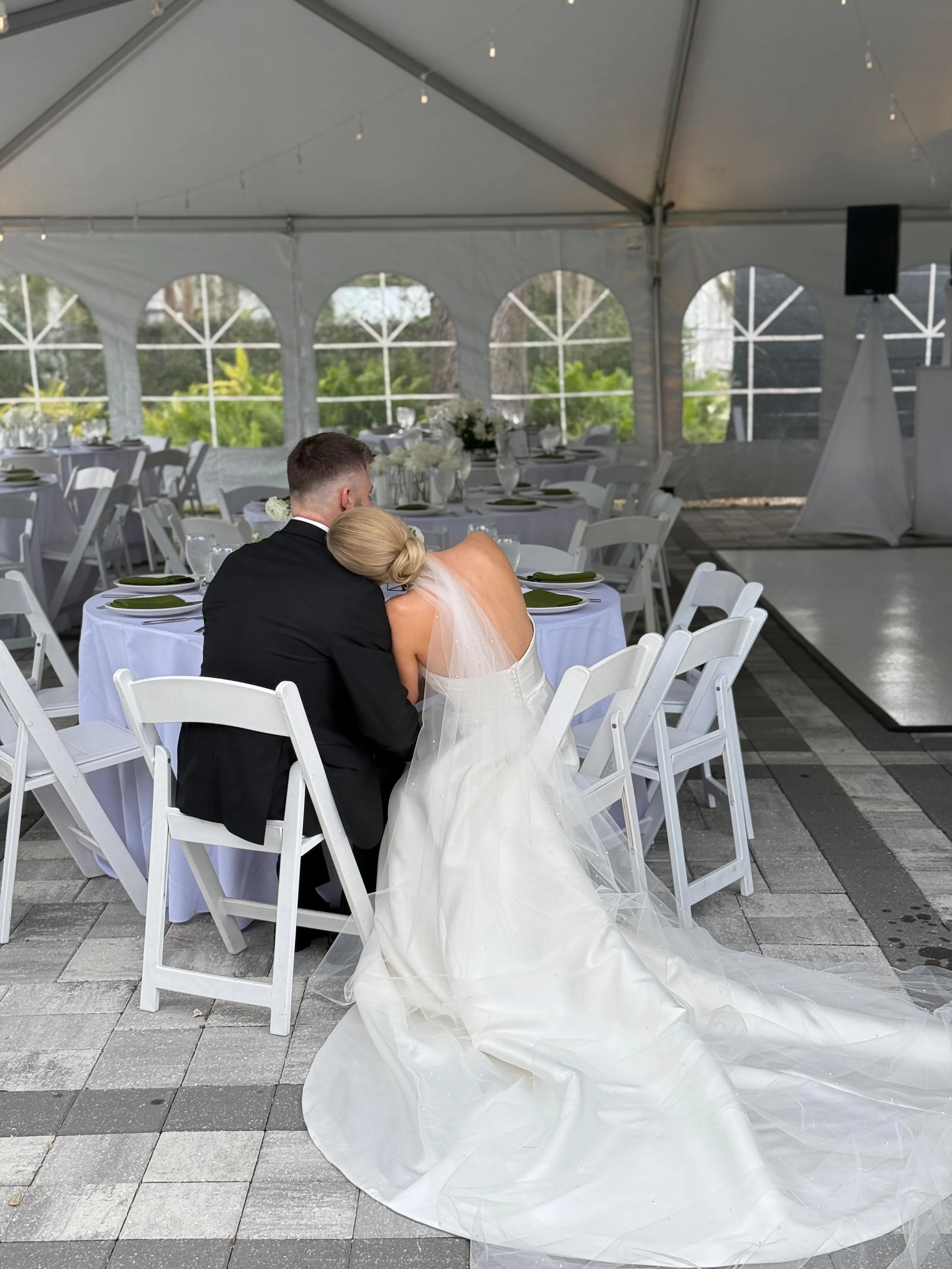 bride leaning on groom, sitting together at their reception venue