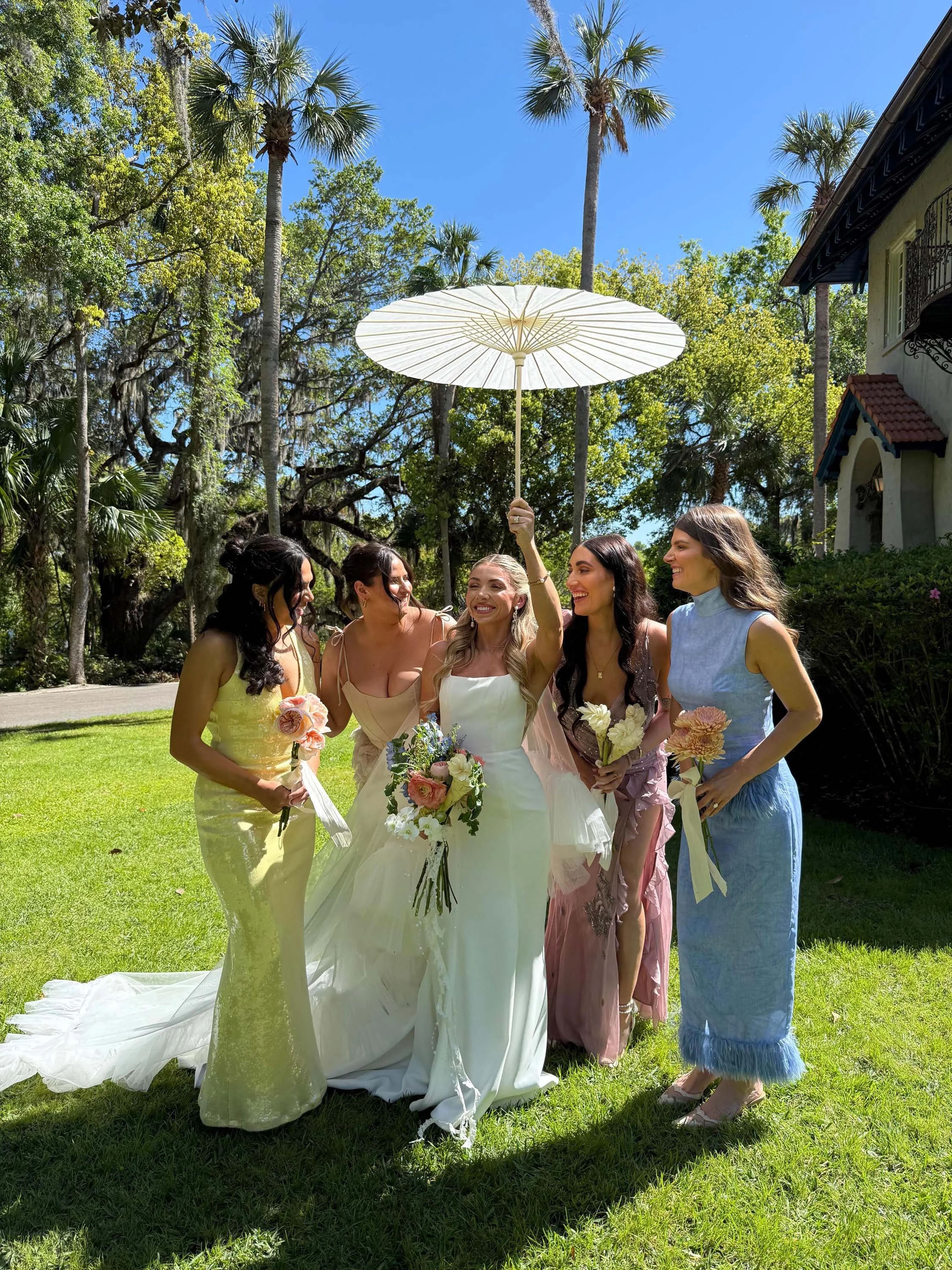 bride holding up a parasol and smiling with her bridal party