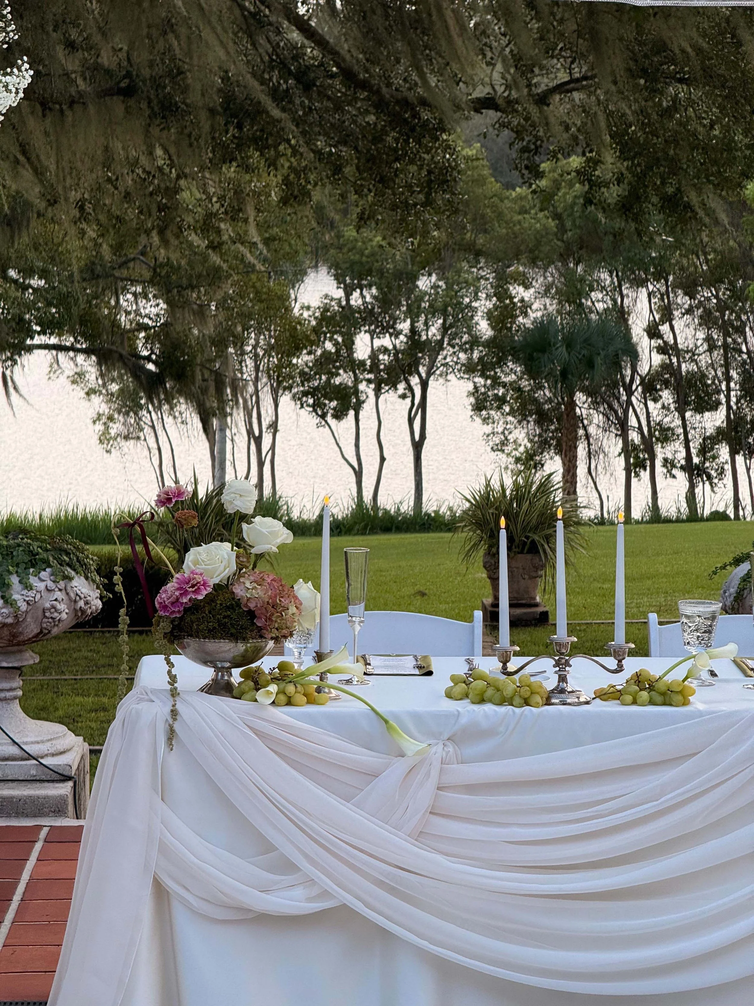 wedding tablescape next to a river with grapes and candle sticks
