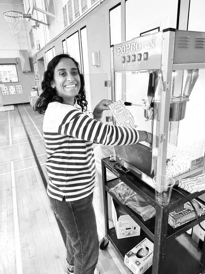 A woman smiling and operating a popcorn machine.