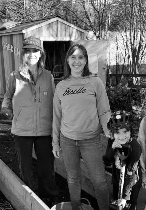 Three women and a young girl pose during a break from working in the Sabin Elementary School community garden.
