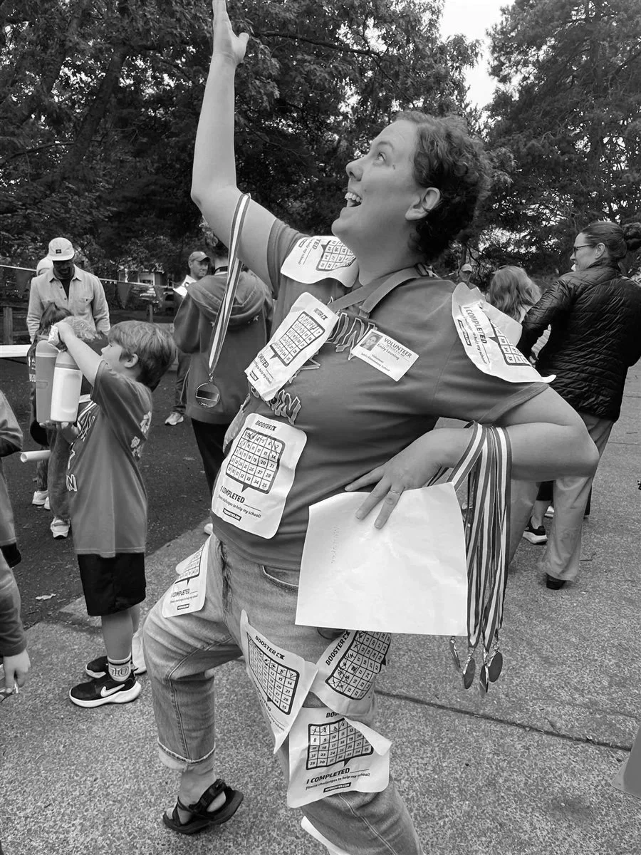 A woman covered in racer stickers after a school fun run.