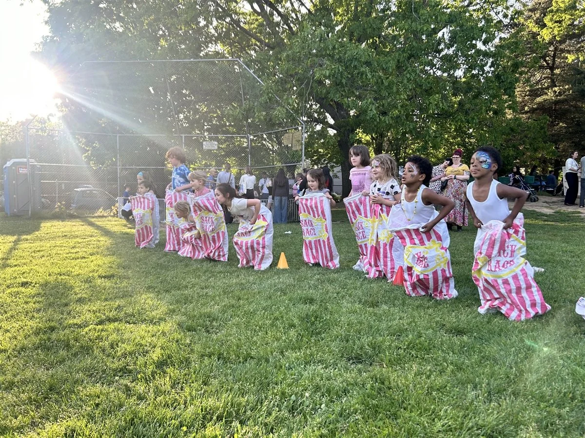 Young students competing in a sack race at the Sabin Spring Carnival.