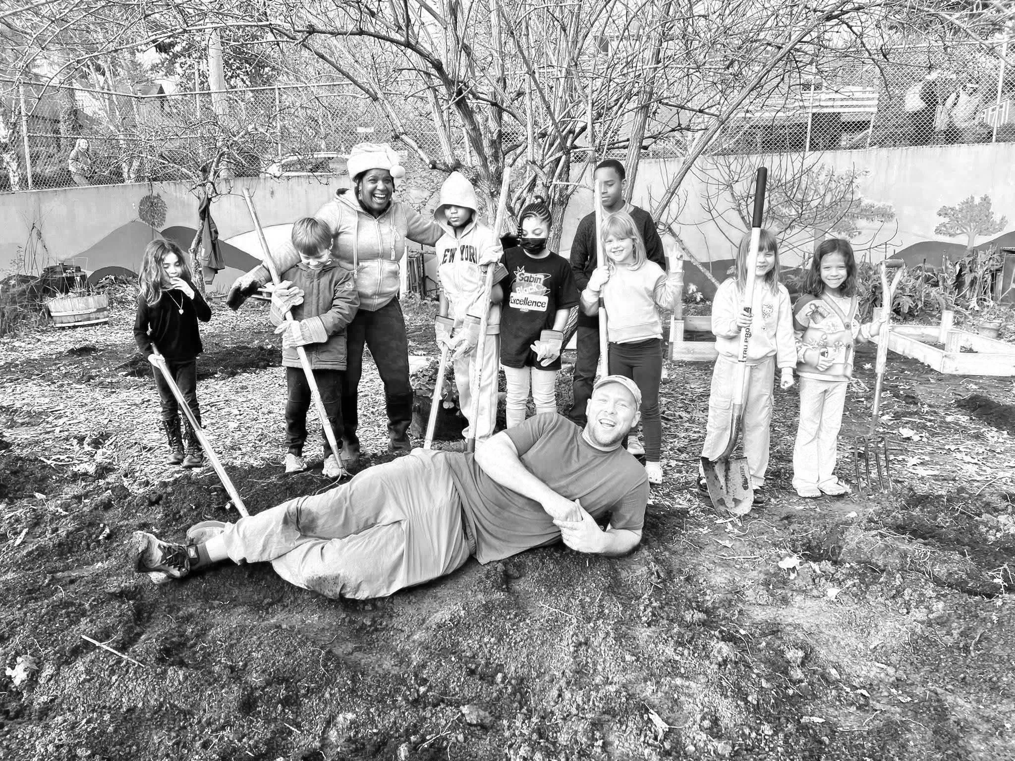 Group of children and adults posing proudly after a day of working in the Sabin garden.