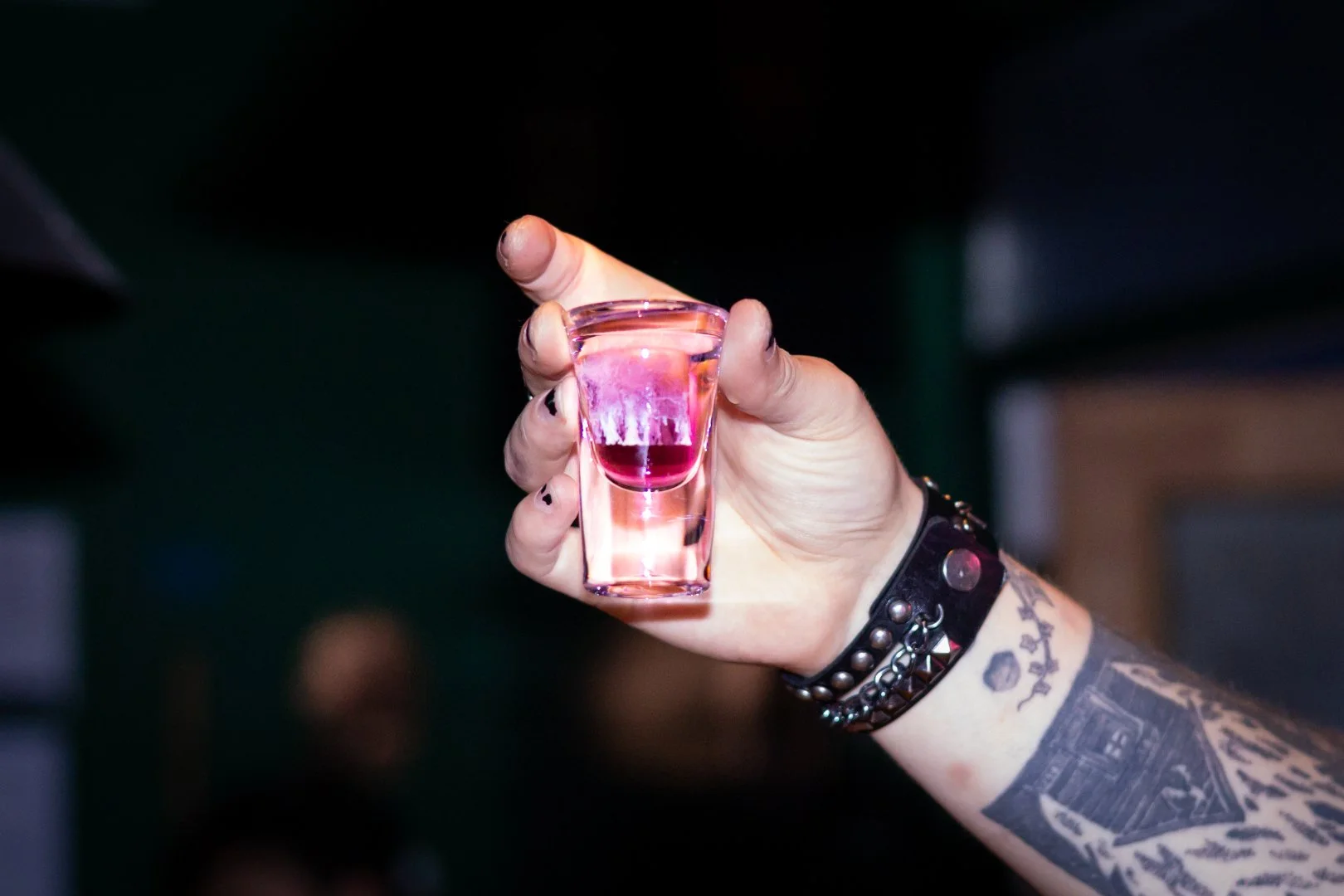 A bartender holds up a shot of alcohol. Photo by Justice Bekke.
