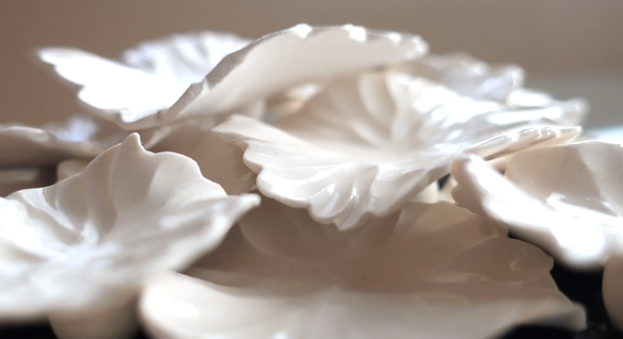 Close-up of white, decorative ceramic or plaster flower petals with detailed texture and ruffled edges.