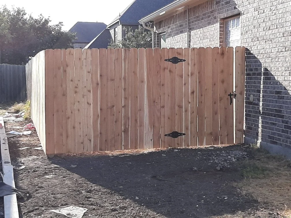 Wooden fence with a gate that we built next to a brick house.