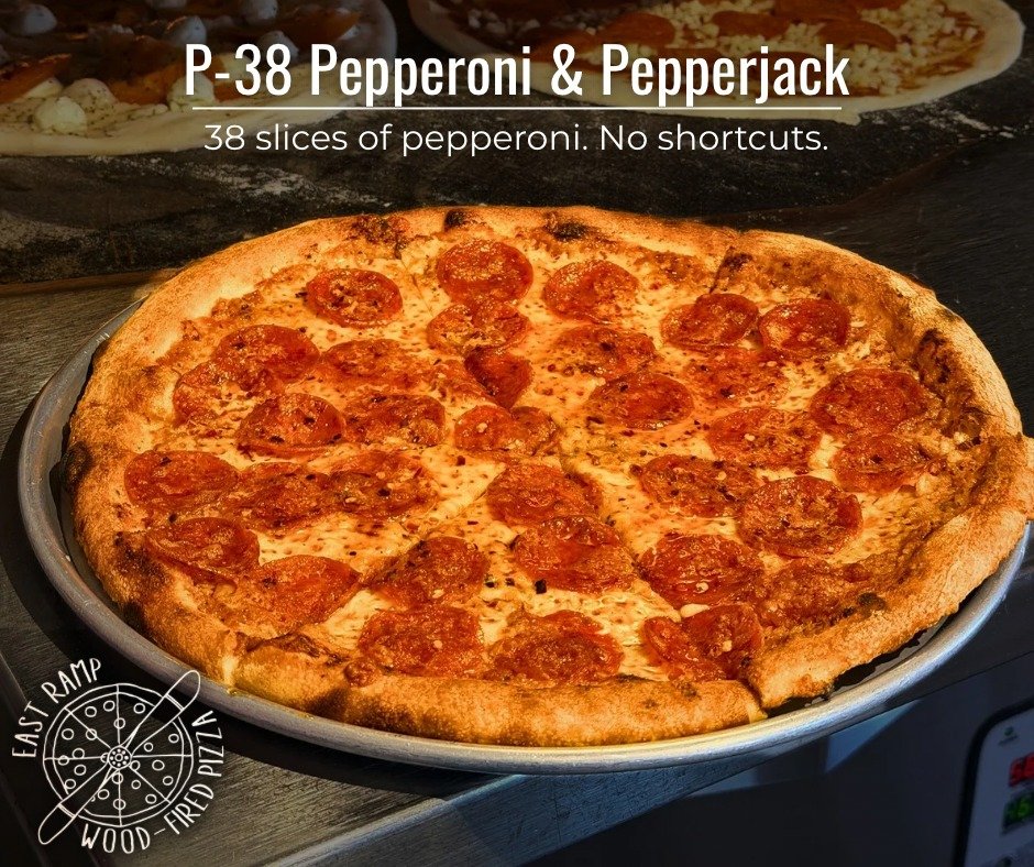 A pepperoni pizza with 38 slices on a gray tray, with a second pizza visible in the background.