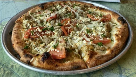 Pizza with chicken, tomato, onion, and cheese on a round metal tray